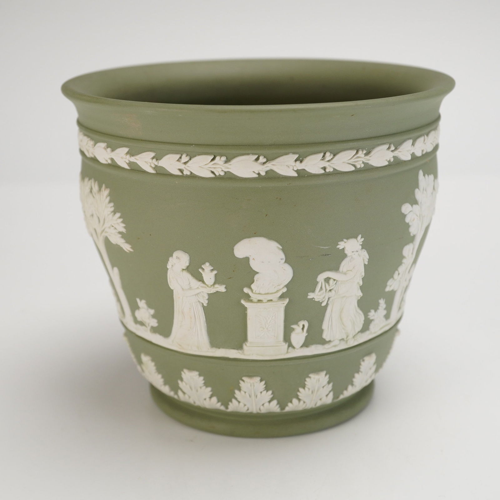 Wedgwood Sage Green Jasperware Neoclassical Vase: The body is finished in sage green and decorated with high-relief applied white molded decoration depicting continuous neoclassical scenes. The primary scene features robed figures set amidst trees an