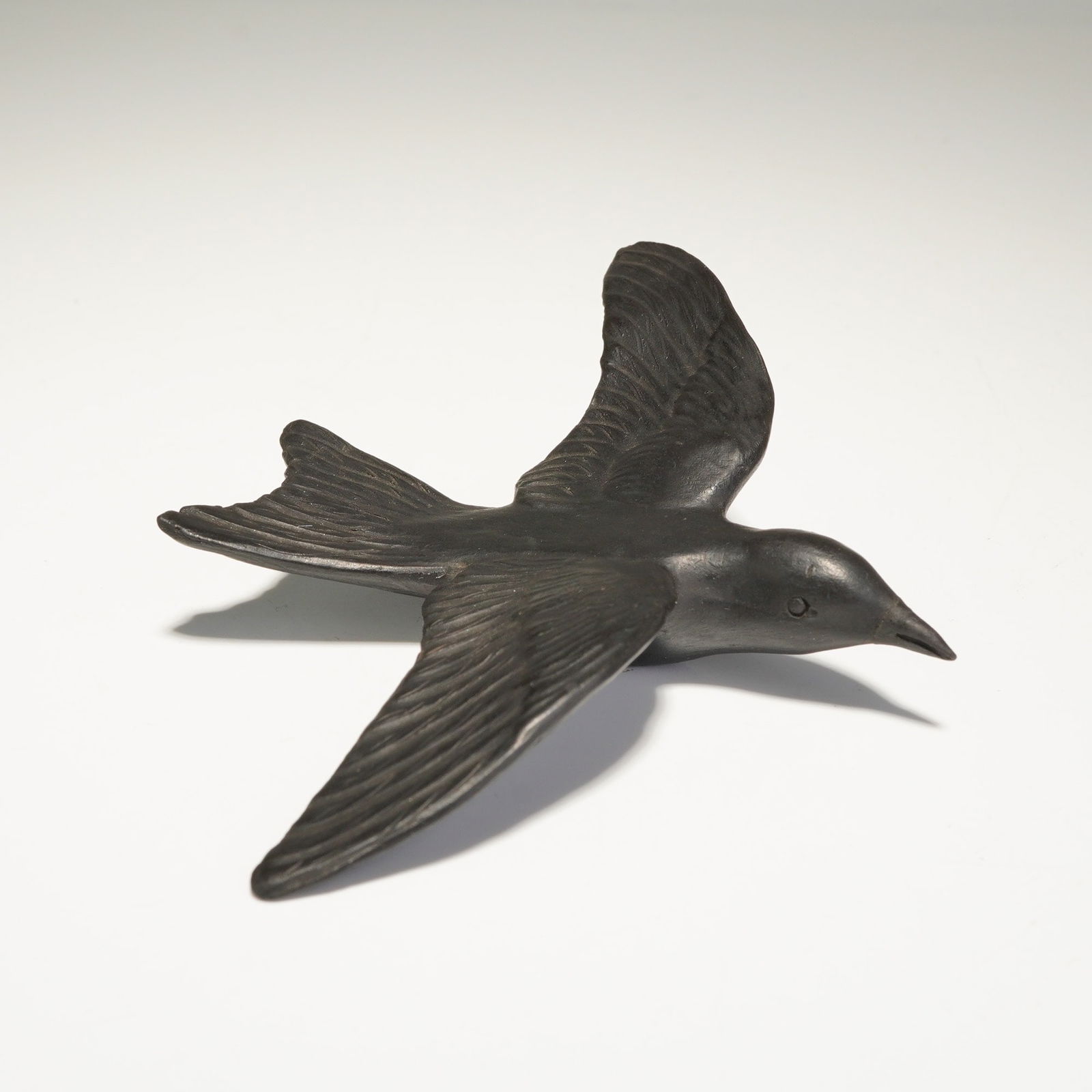 Wedgwood Black Basalt Bird Figurine: A Wedgwood black basalt bird figurine modeled in flight, featuring a sleek form with a forked tail and detailed feathering across the wings. The sculpture is crafted from matte black basalt stoneware.