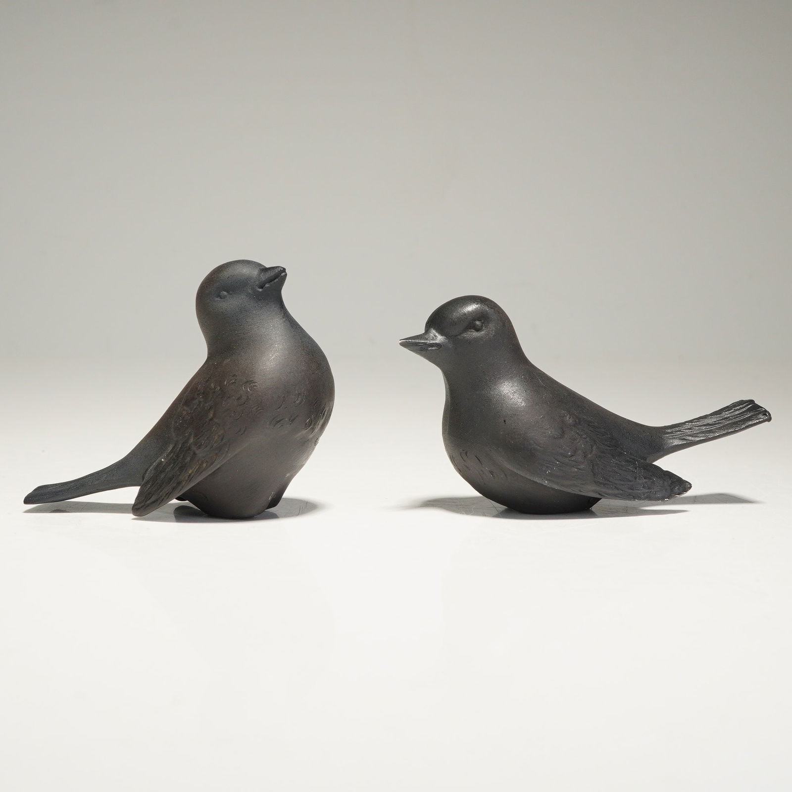 Two Wedgwood Black Basalt Bird Figurines: Two Wedgwood black basalt bird figurines. These modernist-style decorative objects are crafted from a dark, matte-finished stoneware with a rounded, stylized form. The figurines feature incised linear
