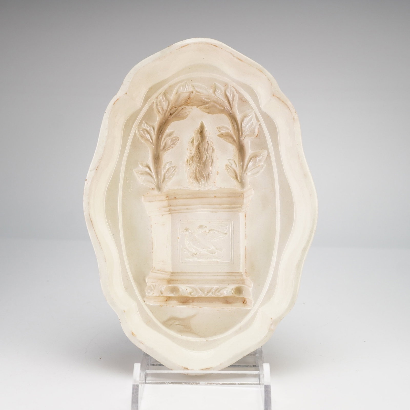 Wedgwood Creamware Confectionary or Jelly Mold: This Wedgwood pottery mold is a creamware confectionary or jelly mold featuring a deeply recessed neoclassical design. The central motif consists of a flaming torch set upon a pedestal decorated with