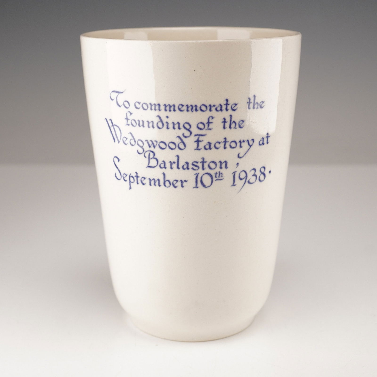 Wedgwood Queensware Barlaston Factory Opening Commemorative Beaker: A Wedgwood Queensware beaker commemorating the founding of the Wedgwood Factory at Barlaston on September 10th, 1938. The off-white, glazed ceramic beaker features the commemorative inscription in blu