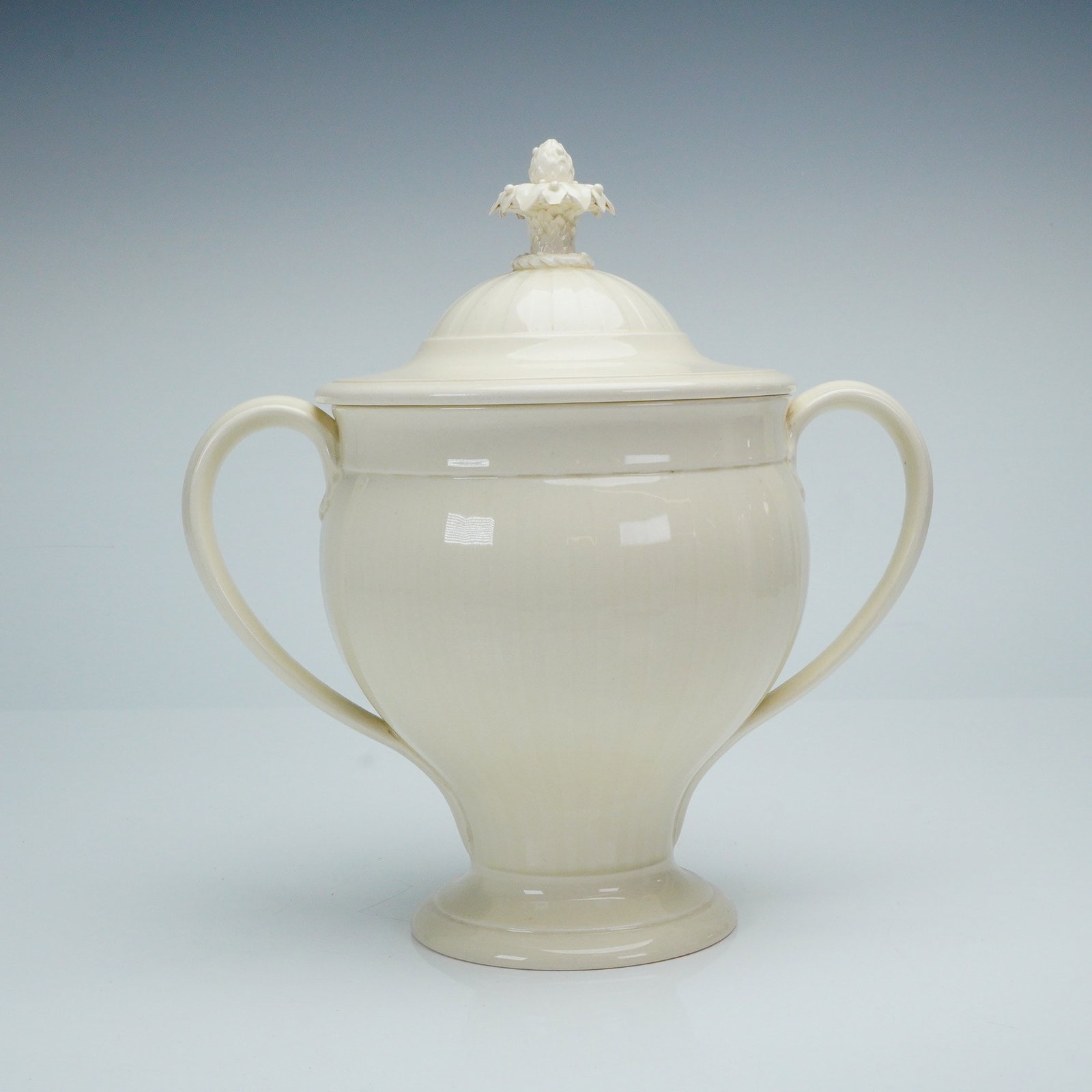 Wedgwood Etruria & Barlaston Creamware Covered Urn: A single covered container produced by Wedgwood at the Etruria & Barlaston factory. The vessel is executed in cream-colored earthenware, commonly known as Queensware, with a glossy glaze, designed in