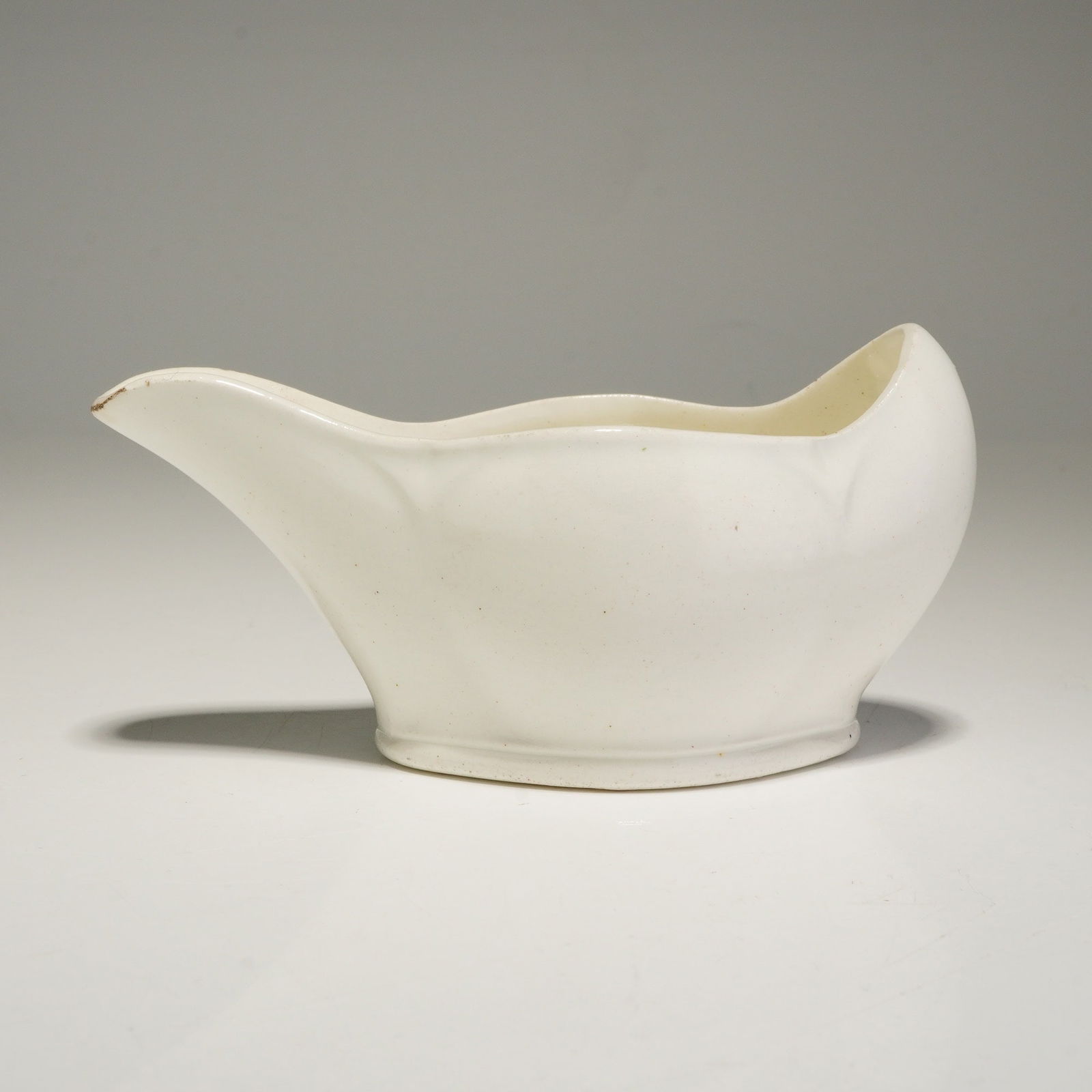 Wedgwood White Glazed Ceramic Pap Boat: A Wedgwood white glazed ceramic small pouring vessel, also known as a pap boat. The item features a minimalist design characterized by a long, tapered spout and a high, sweeping rear rim. The undersid