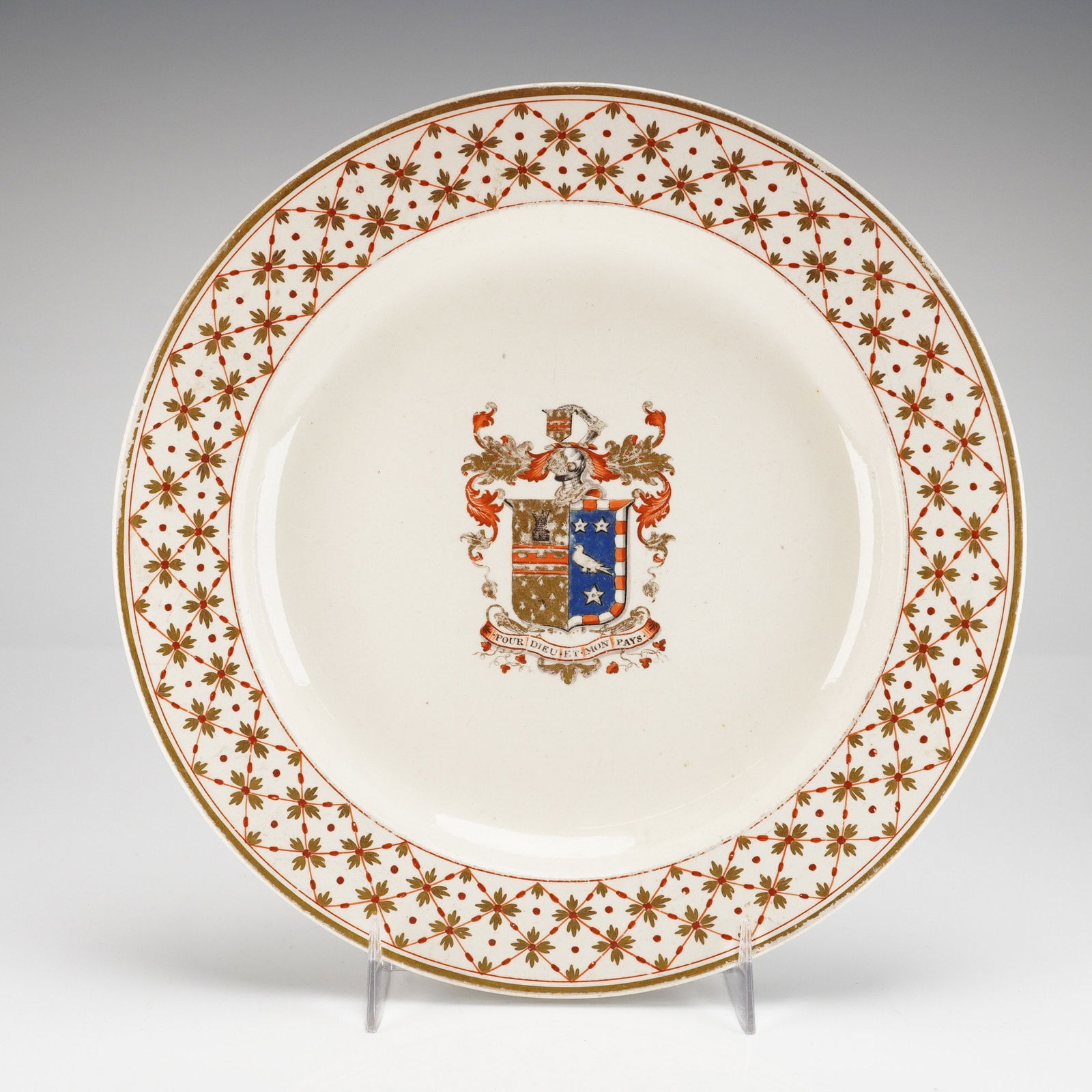 Wedgwood Creamware Armorial Plate: The central coat of arms is decorated in polychrome enamels in shades of orange, blue, brown, and gold, and includes the motto DIEU LE DIT ET MON PAYS. Surrounding this is a wide border featuring a re