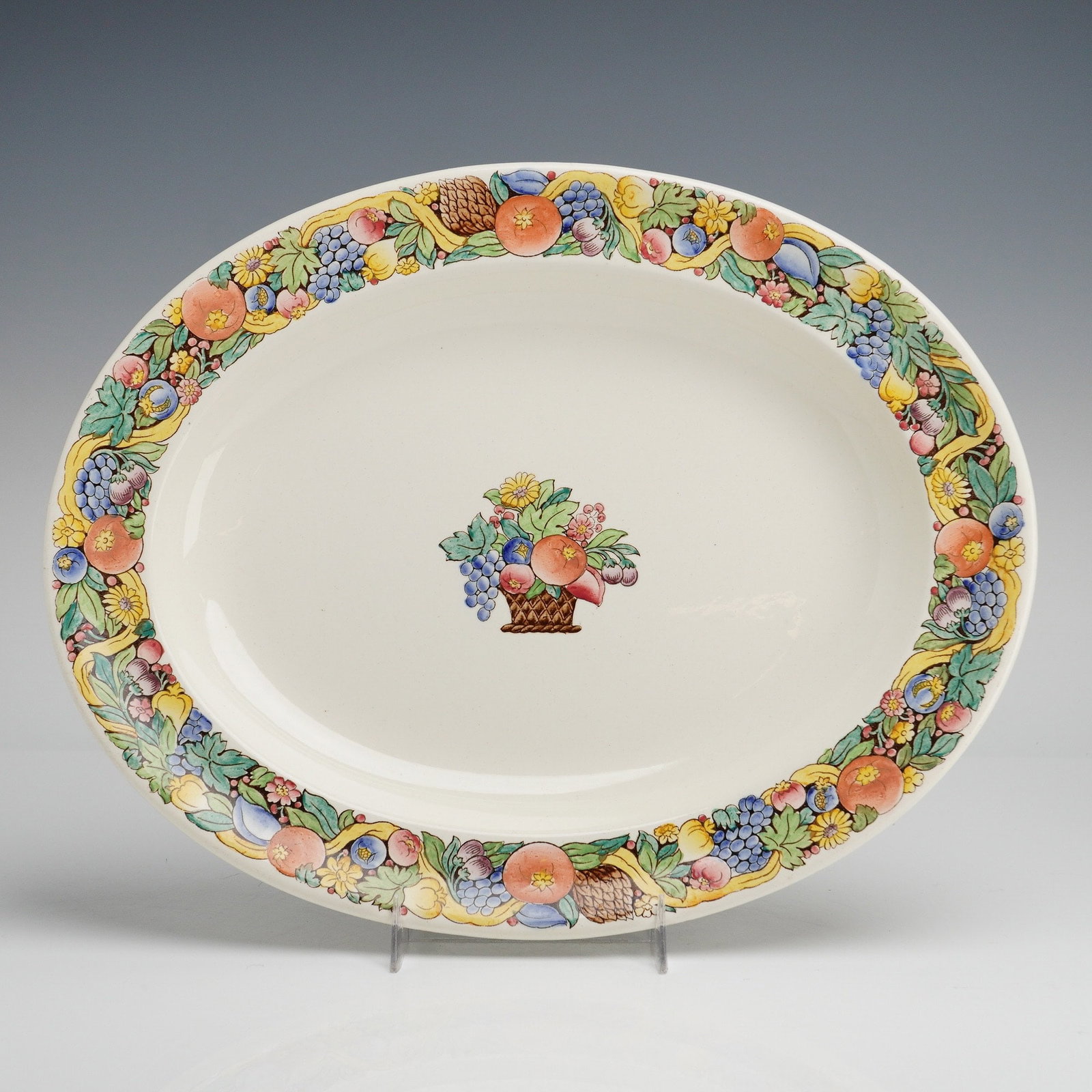 Wedgwood Manilla Pattern Creamware Oval Serving Platter: A Wedgwood creamware oval serving platter in the Manilla pattern. The piece features a central polychrome transfer-decorated motif of a fruit basket. A wide border depicts a variety of fruits, flowers