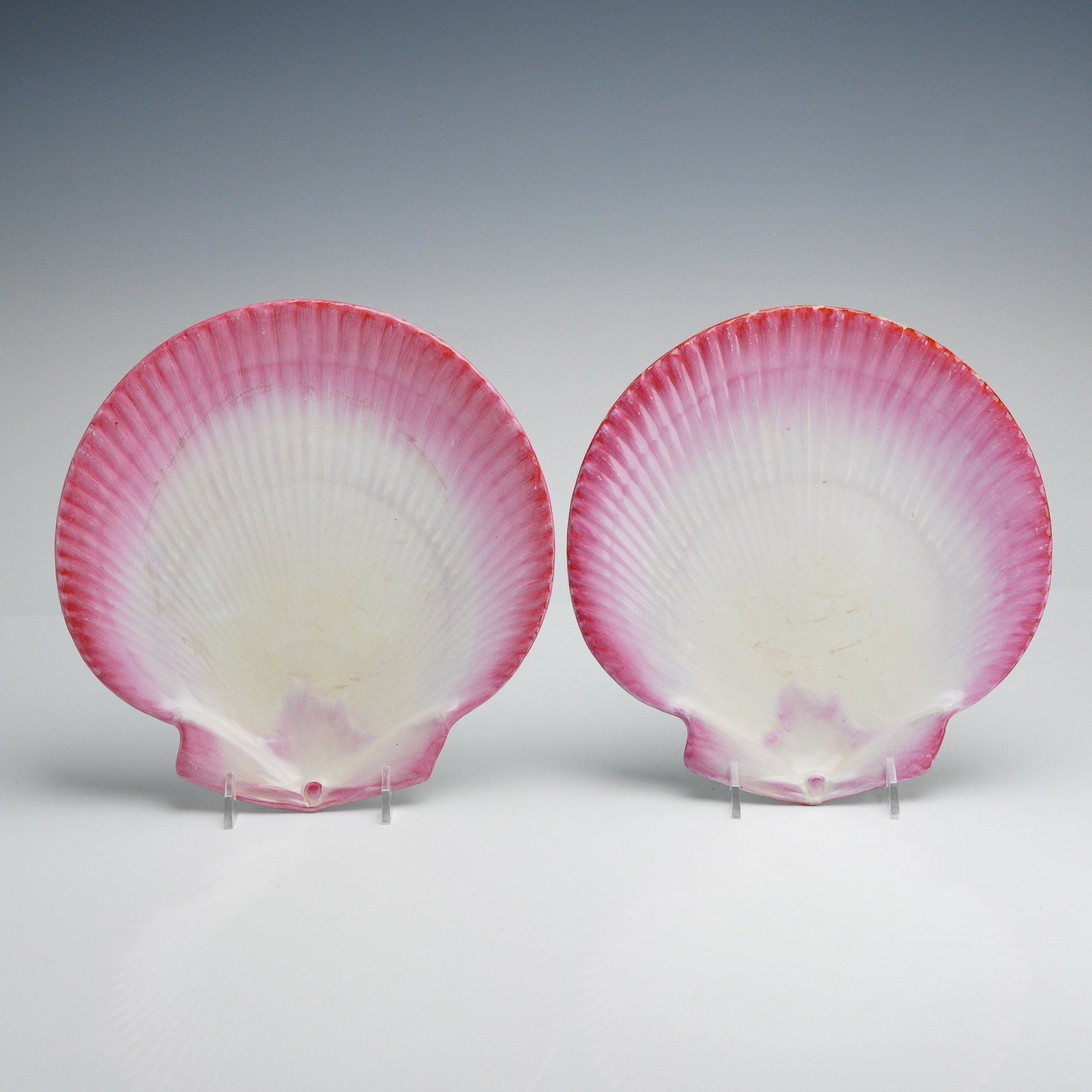 Wedgwood Pink Nautilus Pearlware Scallop Shell Plates: A pair of English pearlware dessert plates manufactured by Wedgwood, part of the celebrated Nautilus collection. Each plate is expertly molded in the form of a scallop shell featuring characteristic r