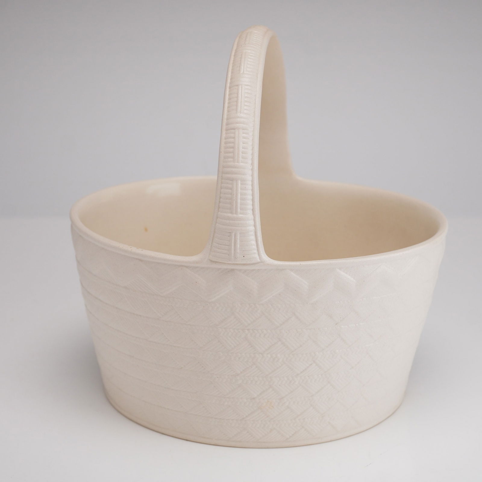Wedgwood Constance Spry Creamware Basket Planter c. 1939: A Wedgwood creamware basket-form planter or flower vessel, dated 1939, designed for Constance Spry. The piece features a matte off-white glaze over a molded earthenware body. The oval vessel and fixed