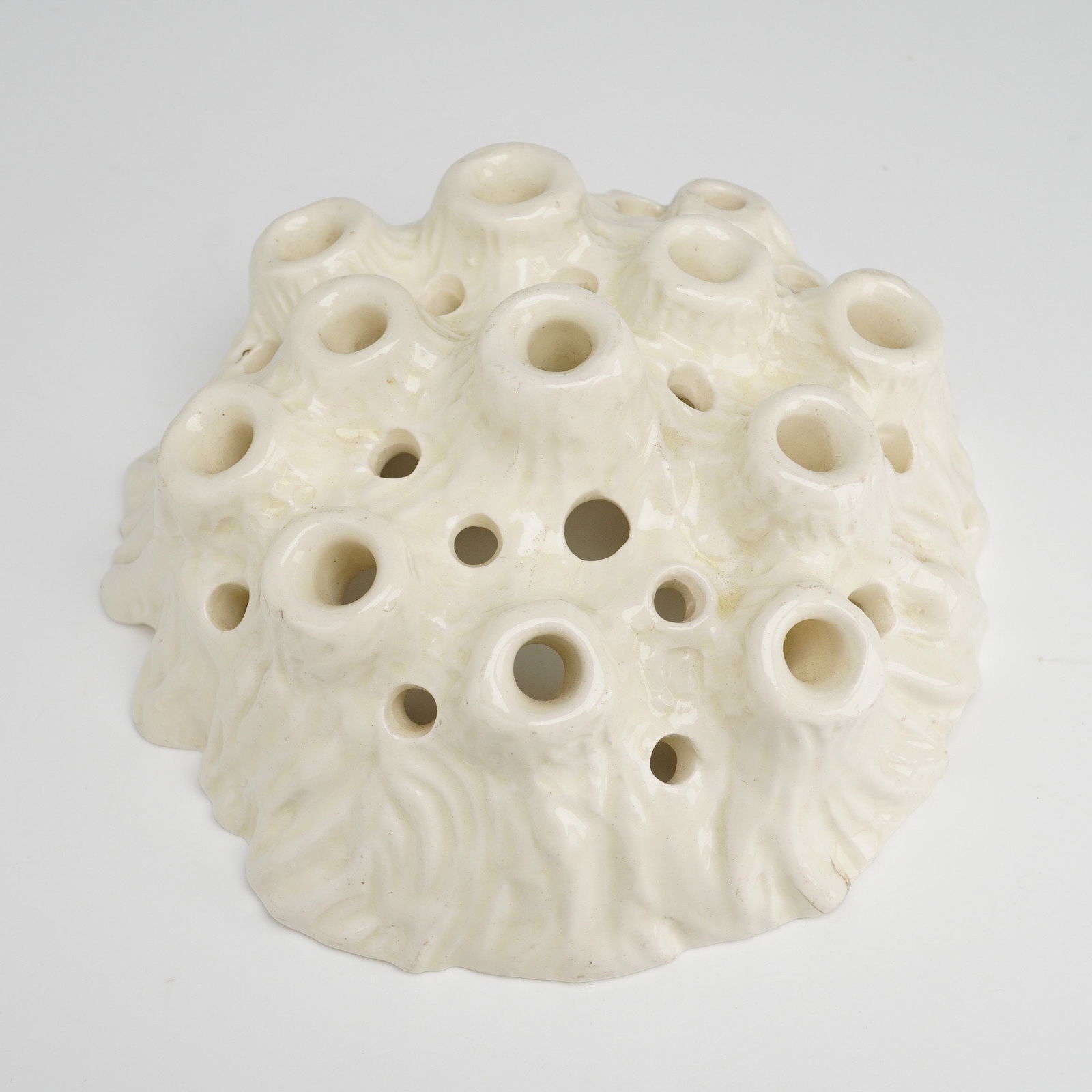 Wedgwood Porcelain Tree Trunk Flower Frog: A Wedgwood porcelain tree trunk flower frog, model number 5067, produced in creamware circa 1934. The object features an organic, mound-like form with a textured surface and multiple raised and recess