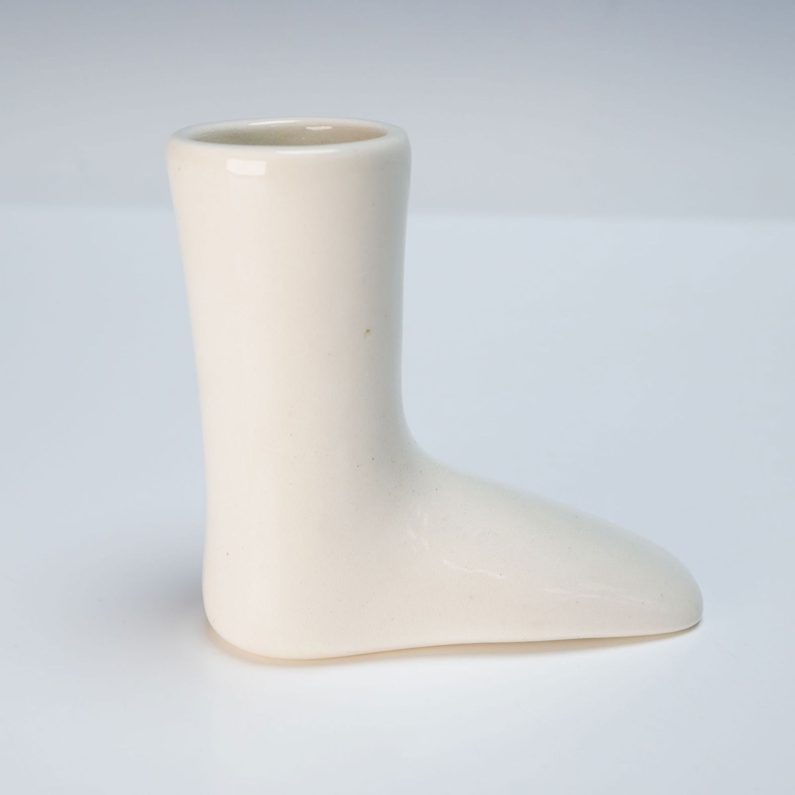 A Wedgwood Ceramic Sock Boot Form: A Wedgwood ceramic sock boot form, dating to the 19th century. Crafted from cream-colored ceramic with a glossy glaze on the exterior and interior. The form is stylized as a foot or boot, suggesting u