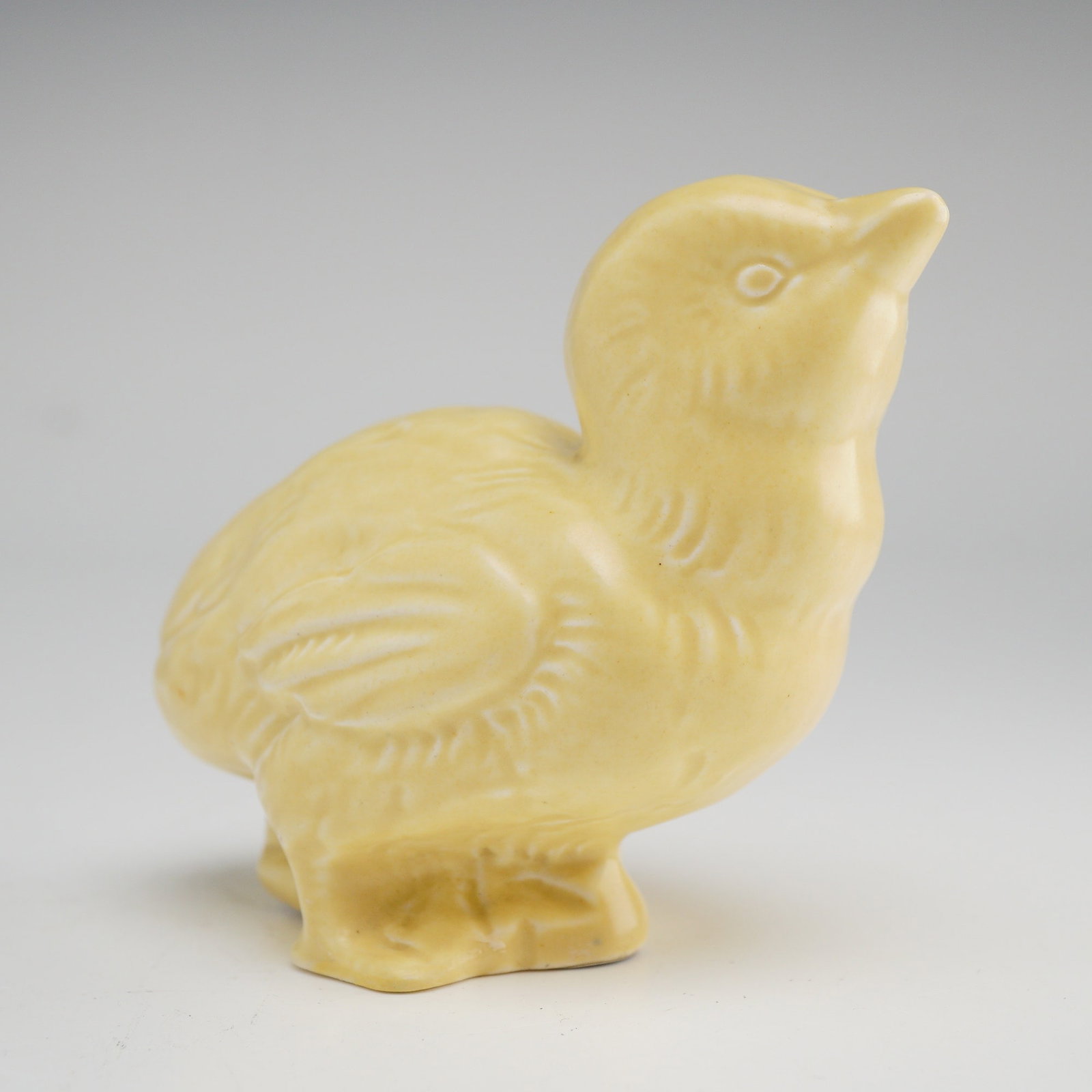 Wedgwood Earthenware Yellow Chick Figurine: Charming ceramic chicken figurine by Wedgwood, rendered in a warm buttery yellow glaze with subtle tonal variation throughout. The piece features a softly modeled form with gently incised feather deta