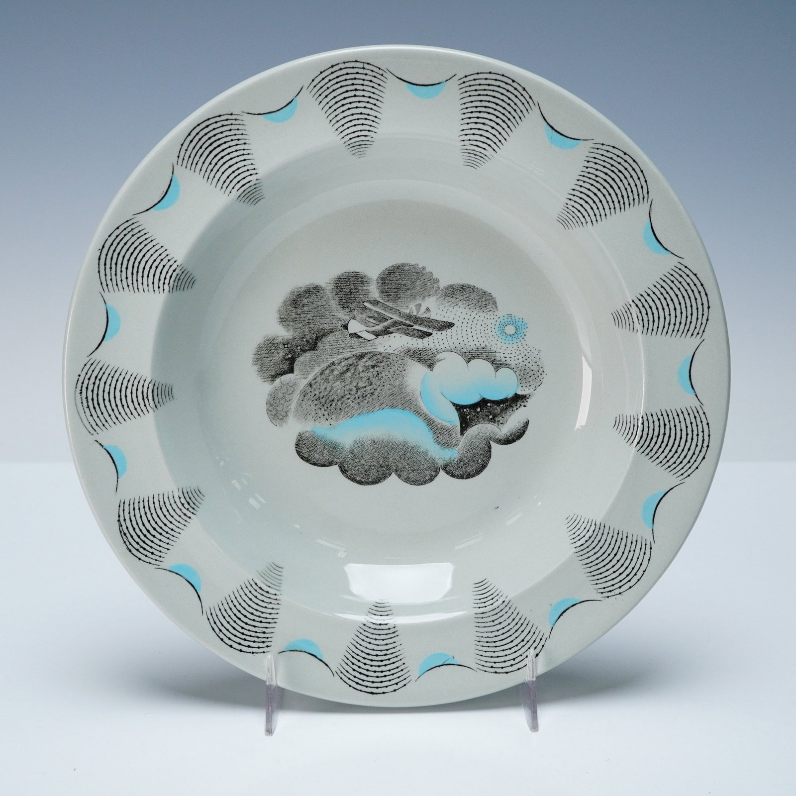 Wedgwood of Etruria & Barlaston by Eric Ravilious Plate, Travel: Transfer-decorated with a central scene depicting an airplane flying above clouds and a hillside landscape, with turquoise enamel accents and a patterned border of radiating black lines and turquoise