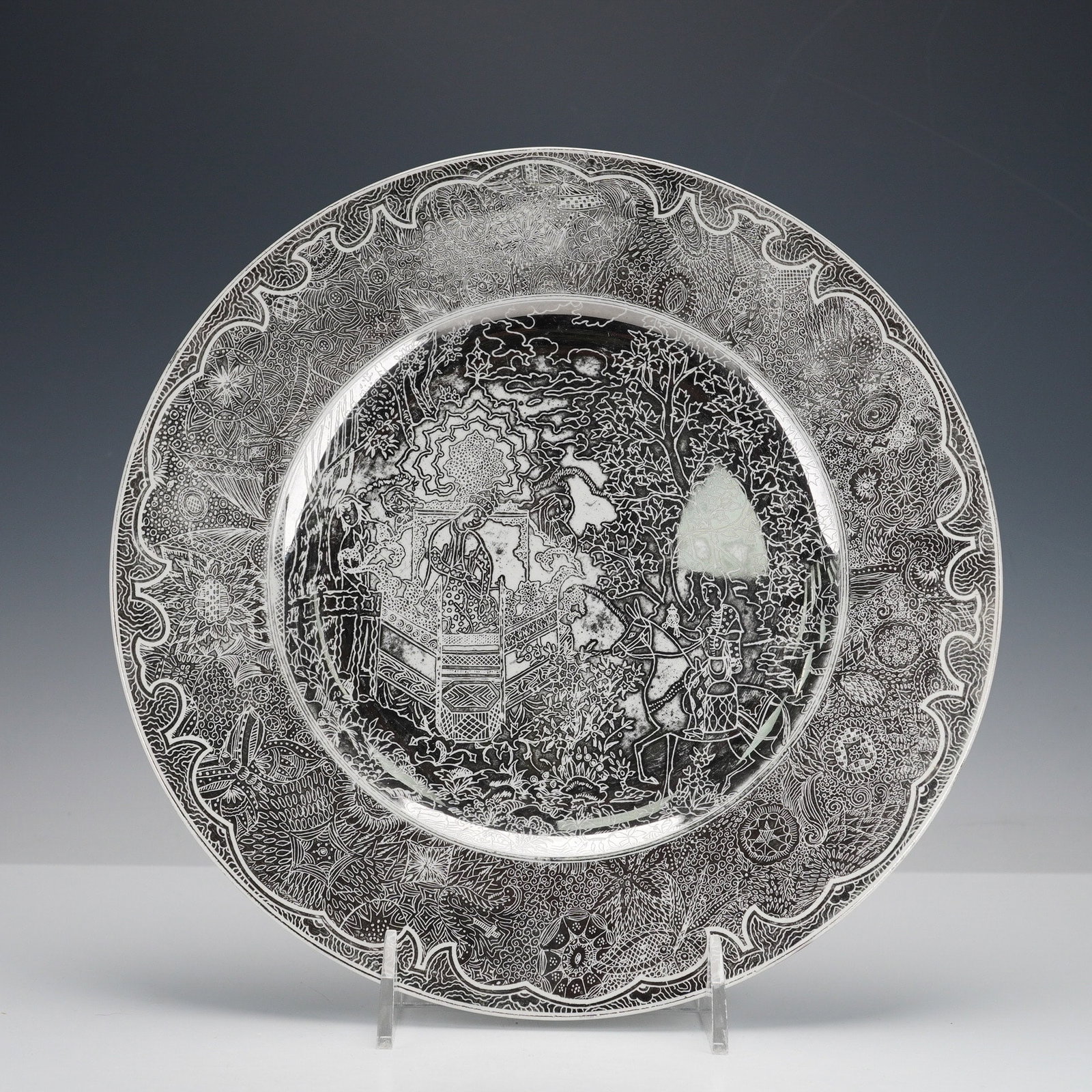 A Wedgwood Black and White Porcelain East Asian Style Decorative Plate: A circular porcelain plate featuring a highly intricate monochrome black and white design. The central well depicts a detailed scenic narrative with figures, architectural elements resembling a pagoda