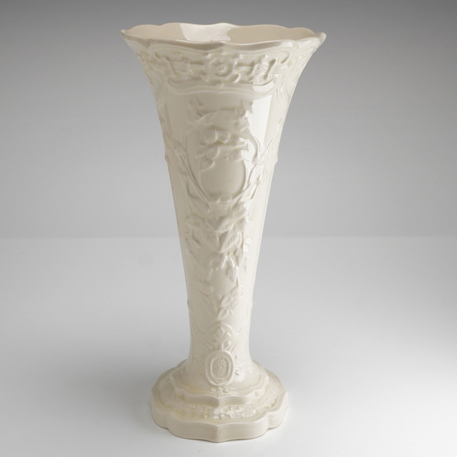 Wedgwood Embossed Queen's Ware Cream on Cream Trumpet Vase: A single vintage Wedgwood Embossed Trumpet Vase executed in cream-colored glazed earthenware. The tall, flaring form features extensive, deeply molded relief decoration in the Neoclassical Revival sty