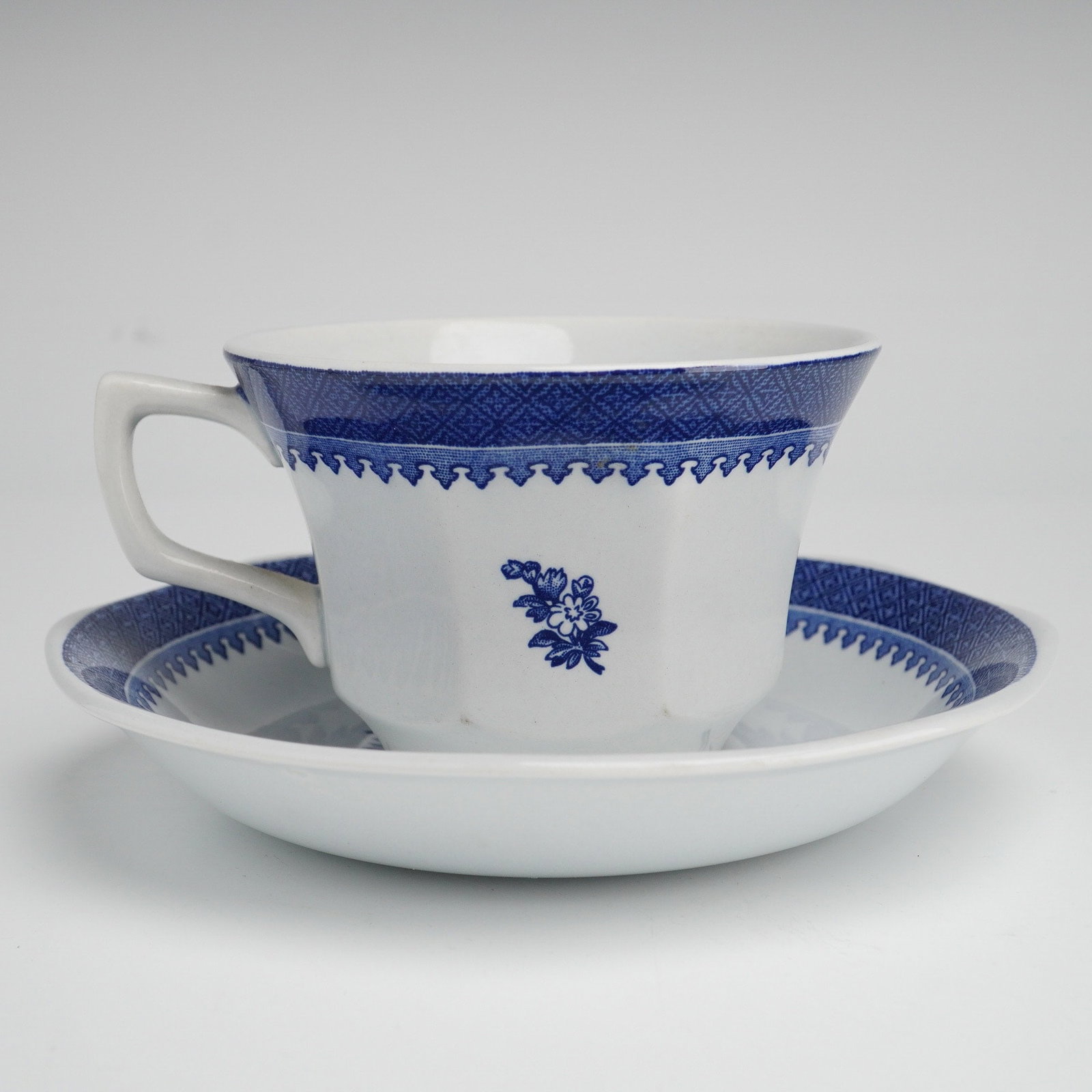 A Wedgwood Springfield Georgetown Collection Cup and Saucer: This cup and saucer set is part of the Georgetown Collection of Wedgwood Springfield pattern. Each piece is crafted from white ceramic and features blue transfer-printed designs, including a wide geom