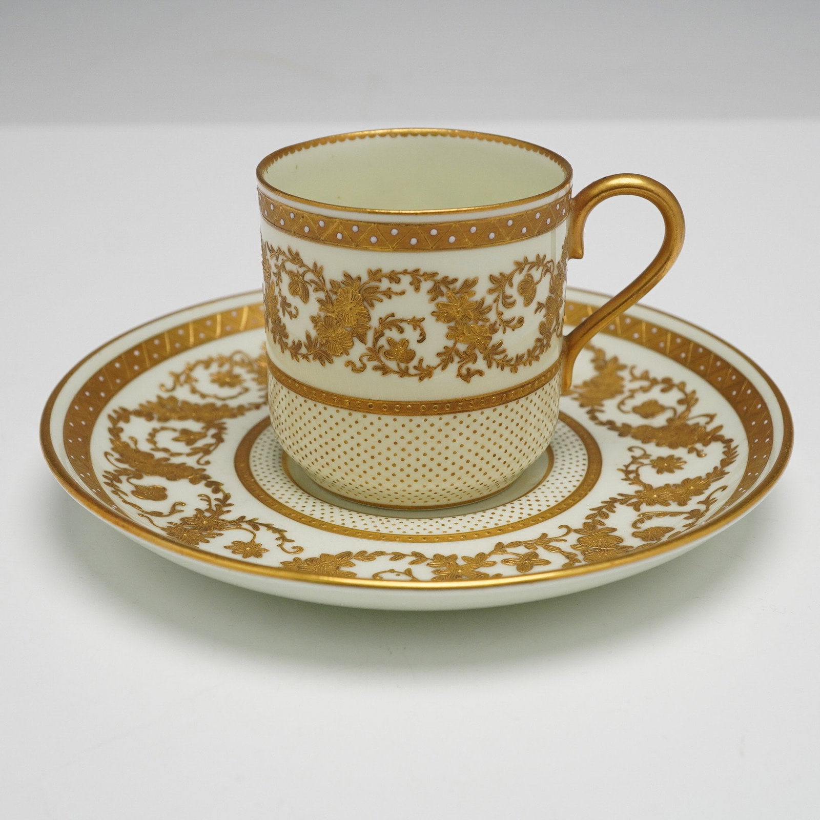 Wedgwood Porcelain Cup and Saucer with Raised Gilt Floral Decoration: A 19th century Wedgwood porcelain cup and saucer extensively decorated with raised gold gilding. The decorative scheme features ornate floral and foliate scrolls, interspersed with geometric dot patte