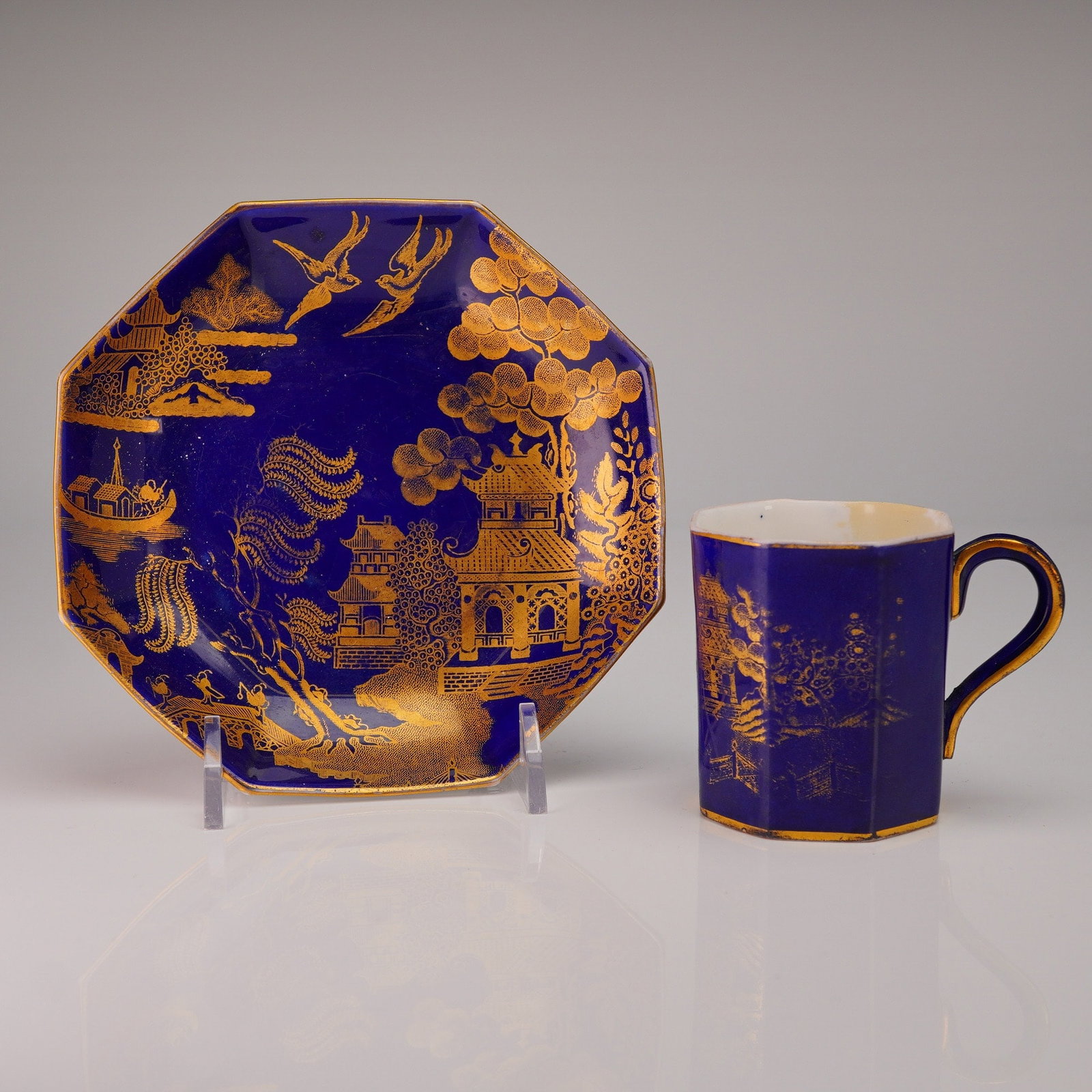 2pc Wedgwood Wonderlust Blue Pagoda Demitasse Cup and Saucer: A pair of Wedgwood demitasse coffee service components, consisting of one octagonal can-shaped cup and one corresponding octagonal saucer. The pieces are executed in bone china featuring a deep cobalt