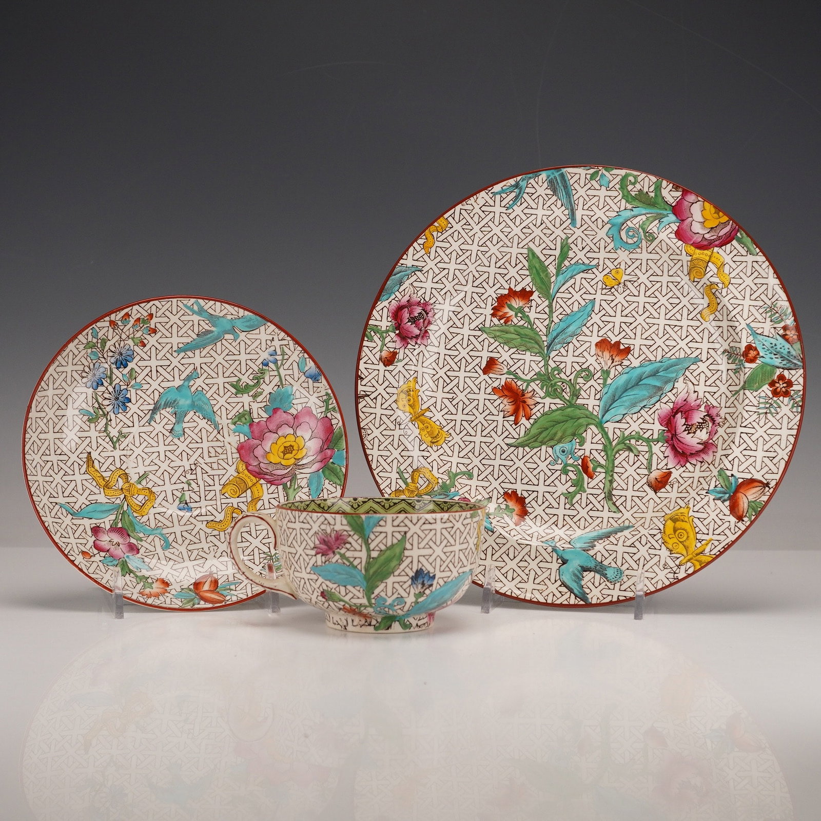 Wedgwood Chinoiserie Birds and Flowers Tea Service Trio Set: Comprising a cup, saucer, and side plate. Each piece is decorated with hand-painted enamel in a trellis, bird, and floral motif. Marked Wedgwood with pattern number A6022. Retains a collection sticker