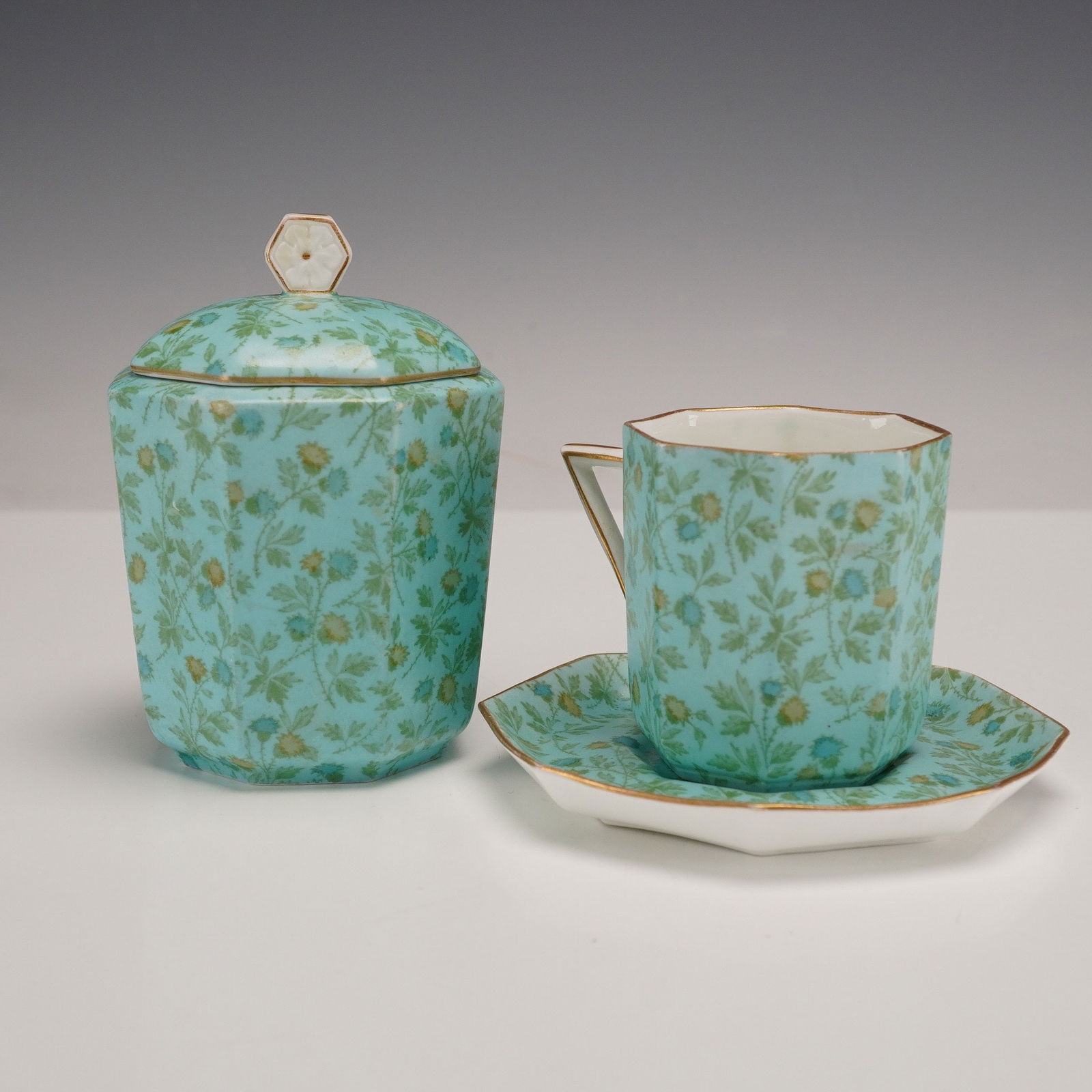 Wedgwood Porcelain Floral Teaware Set: Comprising a cup with saucer and a lidded sugar jar, decorated with a light blue glaze and a green and gold floral pattern, with gilt trim. Marked with Wedgwood backstamp and pattern number 4553, with