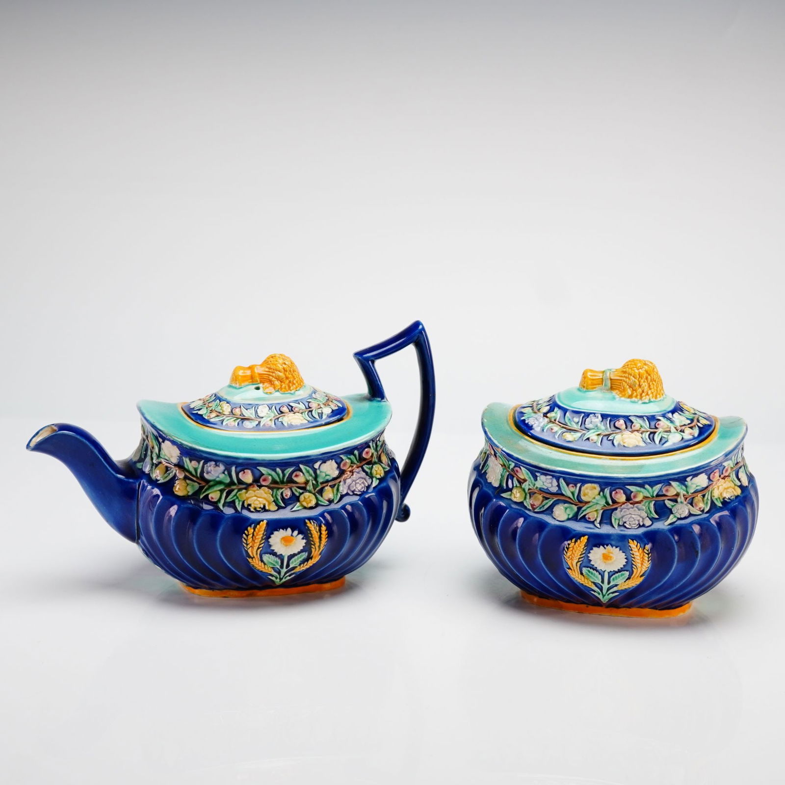 George Jones & Sons, Wheat Pattern, Lidded Creamer and Lidded Sugar Bowl: This two-piece Victorian majolica set is produced by the renowned British manufacturer George Jones & Sons, dating to circa 1874. The set consists of a lidded creamer and a matching lidded sugar bowl,