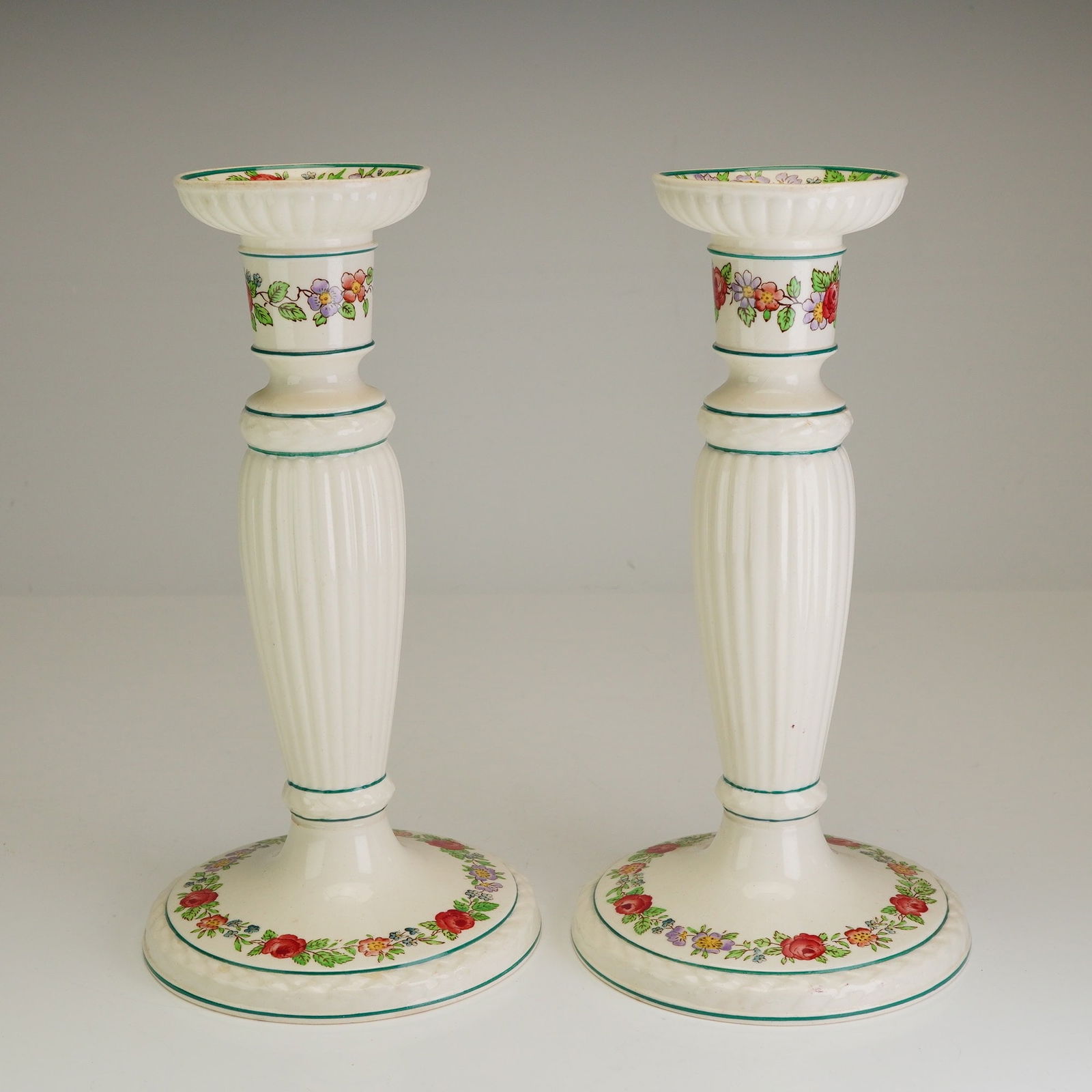Pair of Wedgwood Etruria Belmar Pattern Ceramic Candlesticks: A pair of Wedgwood ceramic candlesticks in the Belmar pattern, featuring a molded neoclassical form with a cream-colored glaze. Each candlestick is designed with a fluted central column and a flared,
