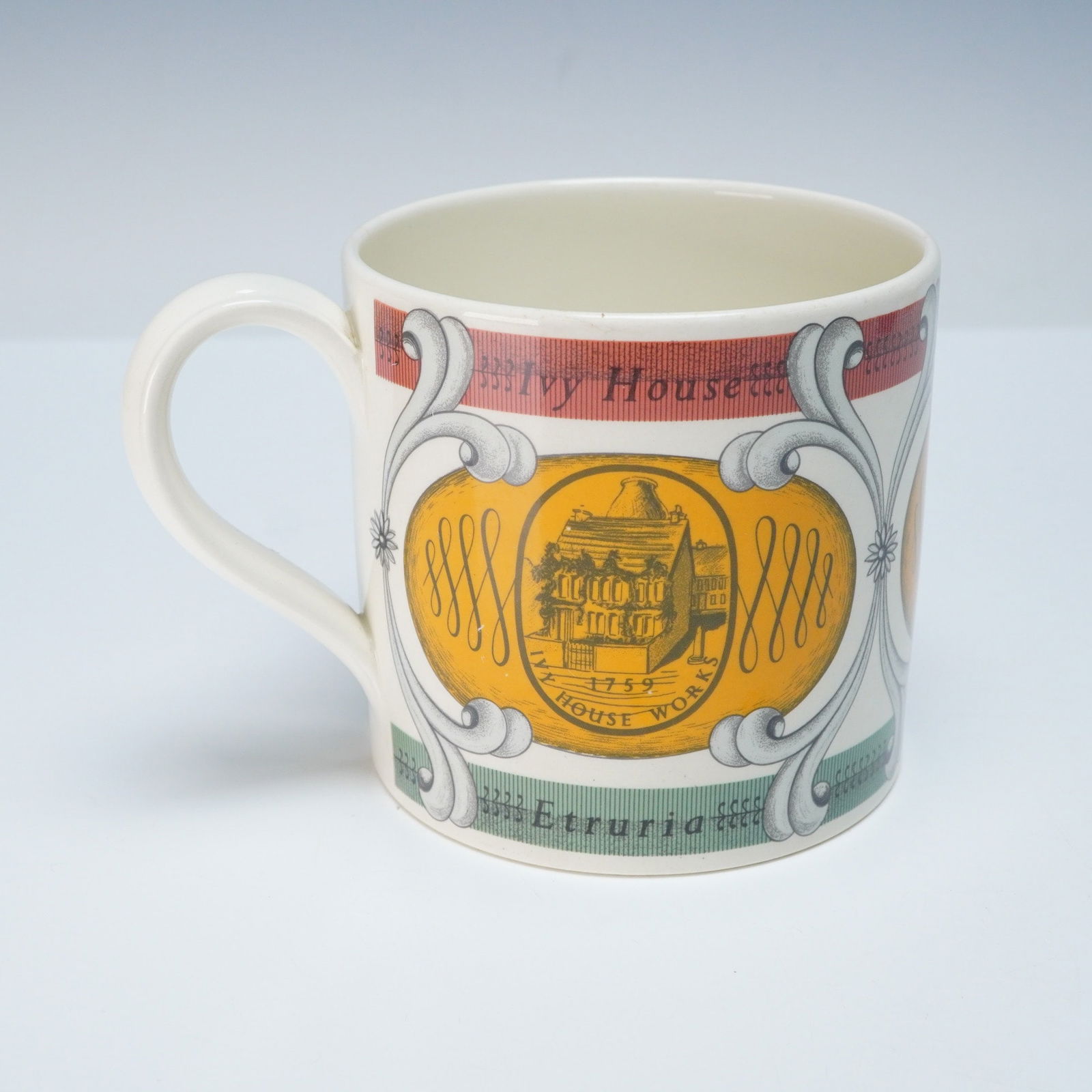 Wedgwood Bicentennial Commemorative Mug, 1759-1959: A Wedgwood Bicentennial Commemorative mug, crafted from cream-colored ceramic and featuring a handle. The mug is decorated with polychrome transfer-printed images within scrolled cartouches. The desig