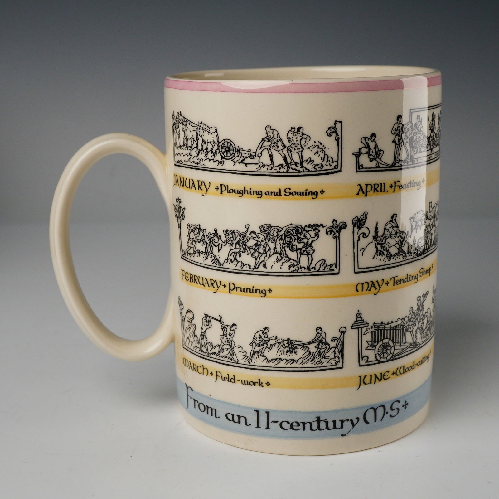 Wedgwood The Old English Calendar Ceramic Mug: A cylindrical ceramic mug by Wedgwood, featuring the transfer-printed pattern known as The Old English Calendar. The mug has a cream/ivory body with a loop handle. The decoration consists of black tra