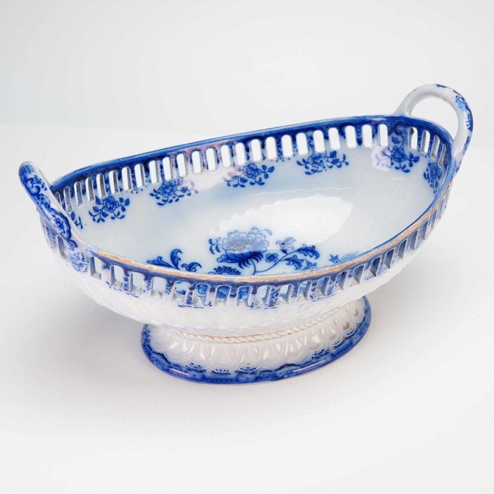 A Wedgwood Blue and White Reticulated Fruit Bowl in the Bamboo Pattern: A Wedgwood pottery blue and white transfer-decorated reticulated fruit bowl in the Bamboo pattern. This boat-shaped footed basket features pierced openwork galleries and two loop handles. The interior