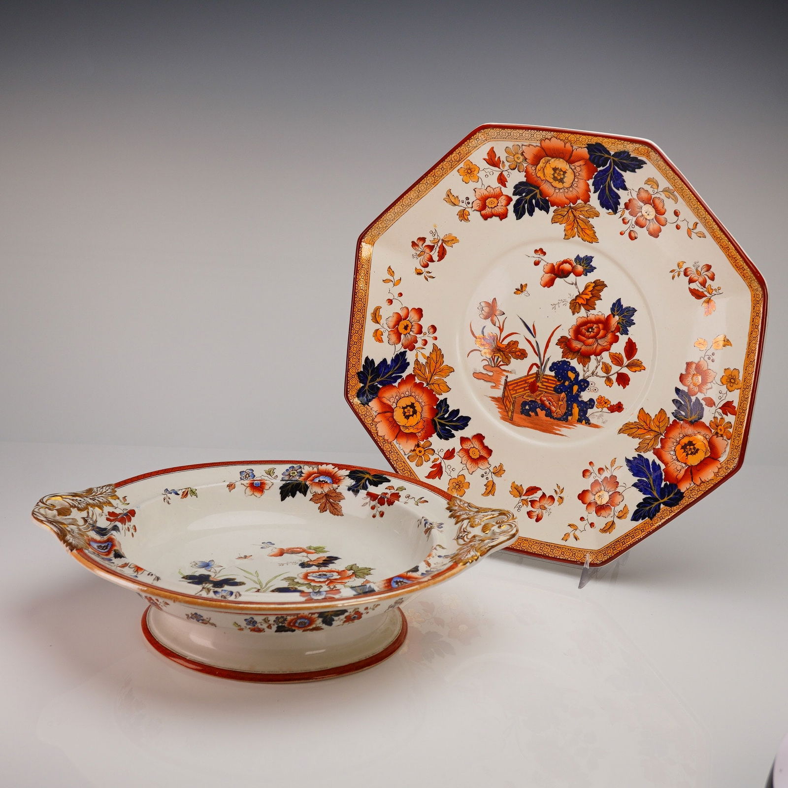 Two Wedgwood Etruria Eastern Flowers Platter and Footed Bowl: The collection consists of a handled, footed oval serving bowl and one octagonal plate. Both pieces features Eastern Flowers pattern decoration utilizing vibrant rust orange, cobalt blue, and red enam