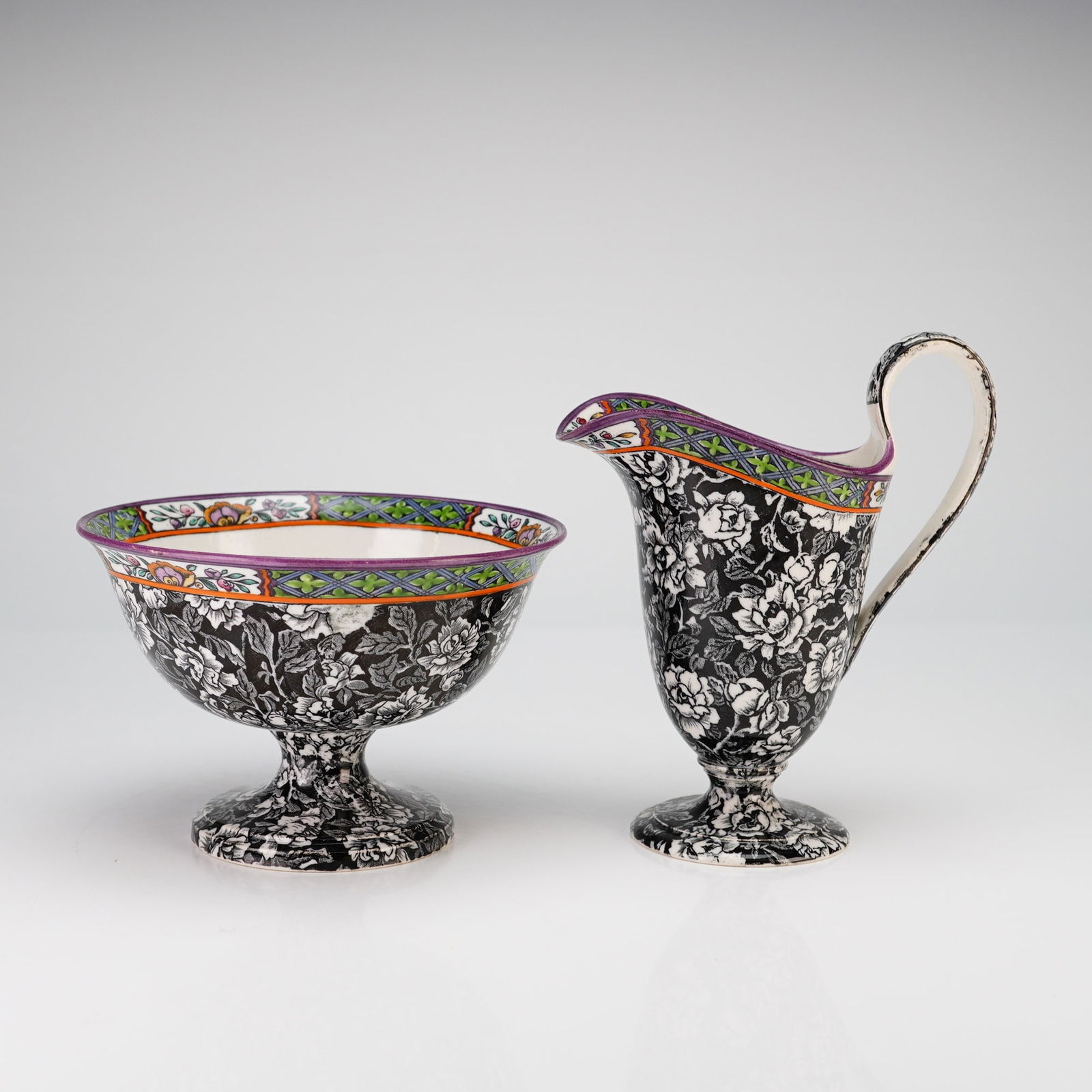 2pc Wedgwood Pottery Small Pedestal Bowl and Small Pitcher: A two-piece Wedgwood pottery set consisting of a small pedestal bowl and a coordinating small pitcher. Both items feature a dense black-and-white floral transferware pattern across the exterior and fo