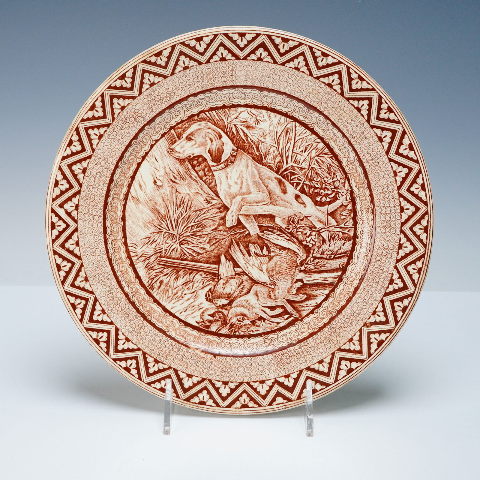 Wedgwood Goodwood Brown Earthenware Hunting Plate, Mekado Border: A Wedgwood Aesthetic Movement Goodwood brown transferware plate, likely earthenware, decorated with a monochromatic reddish-brown transfer print on a cream-colored ground. The central scene depicts a