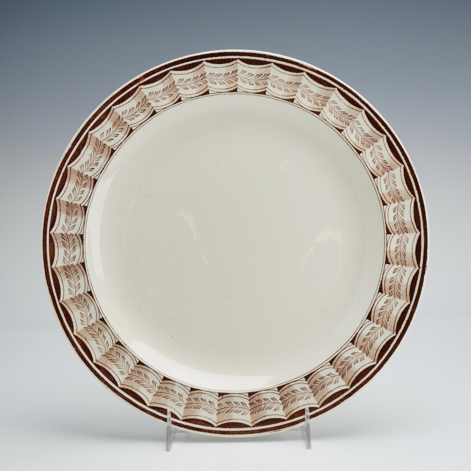 Wedgwood Lag and Feather Plate: A Wedgwood creamware or white earthenware plate featuring a sophisticated brown transfer-printed border in the Lag and Feather pattern. The decoration consists of repeating stylized feather motifs arr