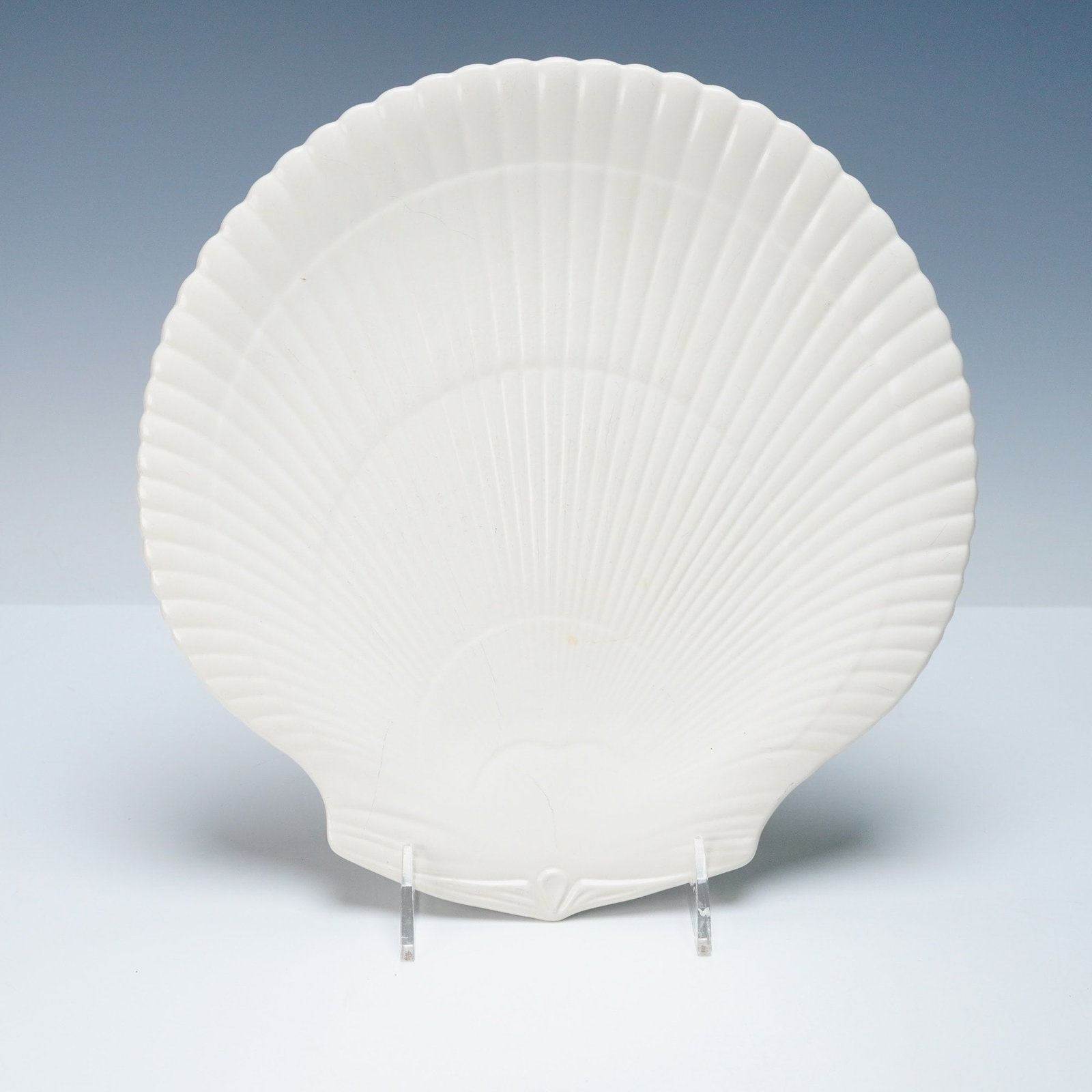 Wedgwood of Etruria & Barlaston Earthenware Plate, Moonstone: Featuring a matte all-white finish with shell motif. Underside marked with the Wedgwood of Etruria & Barlaston backstamp. Retains a provenance sticker from the Ellis Rubin Collection. Dimensions10.75"