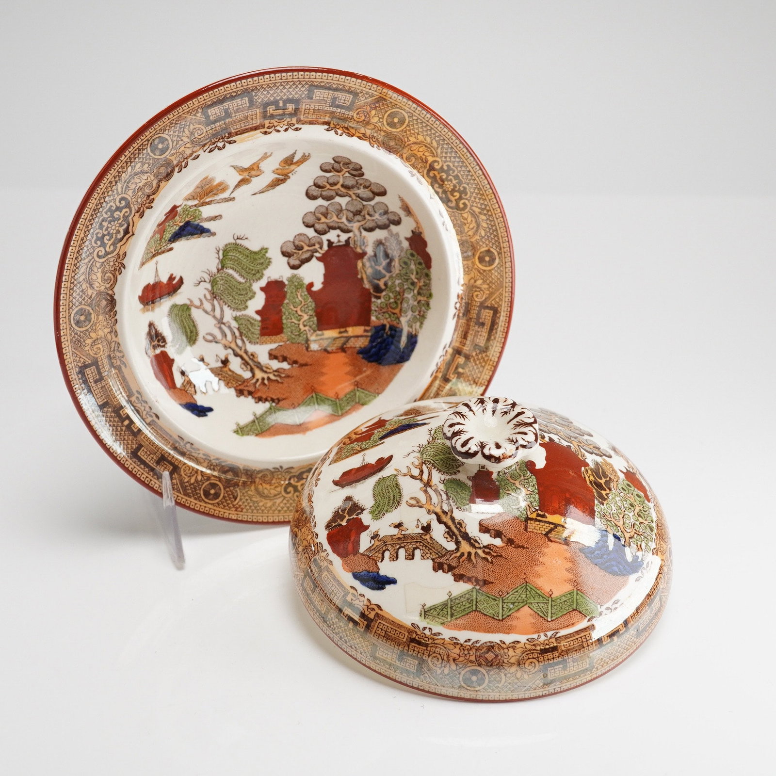 Wedgwood Etruria England Polychrome Willow Covered Serving Bowl: The set comprises a shallow base plate/bowl and a dome-shaped cover topped with a stylized floral finial. The pieces are decorated in a multi-color variation of the traditional Chinoiserie Willow patt
