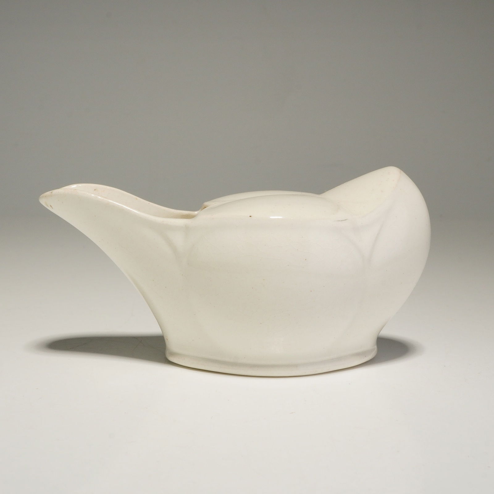 A Wedgwood Small Pouring Vessel: This Wedgwood small pouring vessel is designed in an elongated, boat-like form traditionally used as a pap boat or infant feeder. The ceramic piece is finished in a uniform white glaze and features an