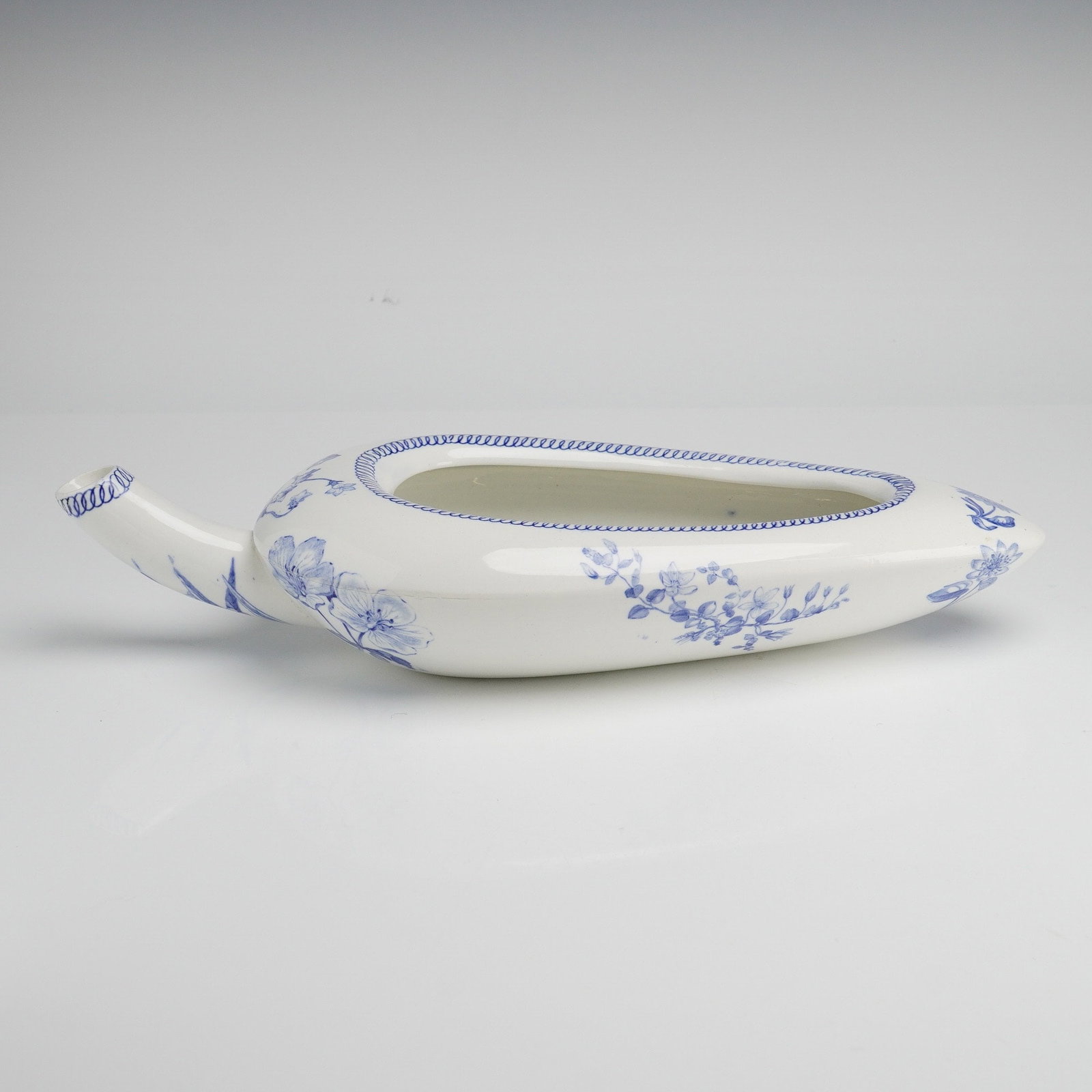 A Wedgwood Blue and White Transfer-Printed Ceramic Bedpan: A Wedgwood blue and white transfer-printed ceramic bedpan. This medical ware item is constructed in a pear-shaped form with an integrated spout and a central oval aperture. The white-glazed ceramic bo