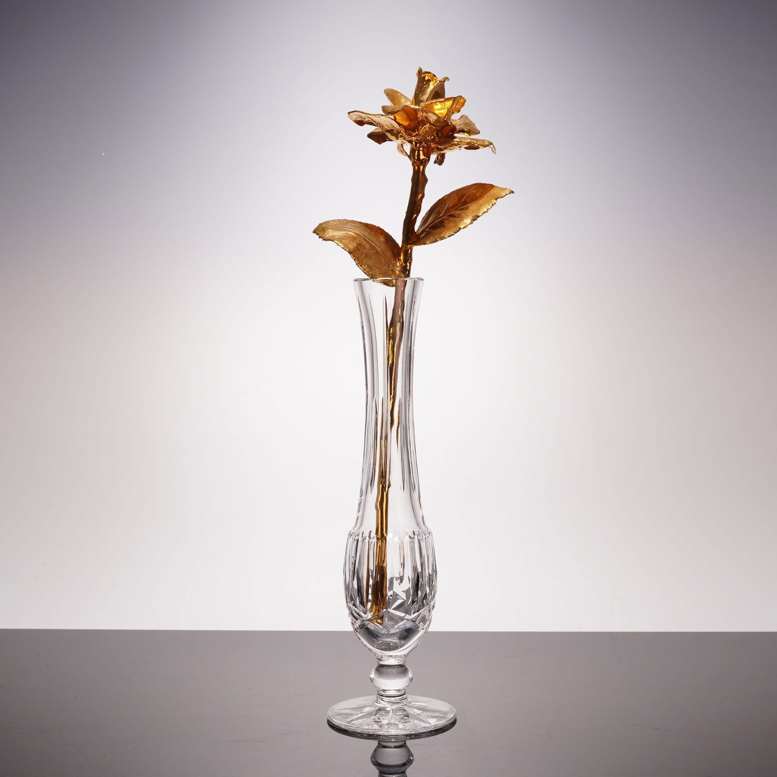 Waterfor Crystal Kildare Bud Vase and Gold-Plated Preserved Rose: This lot features a two-piece decorative set comprising a gold-plated rose, paired with a fine lead crystal bud vase by Waterford. The mouth-blown and hand-cut crystal vase displays vertical fluting a