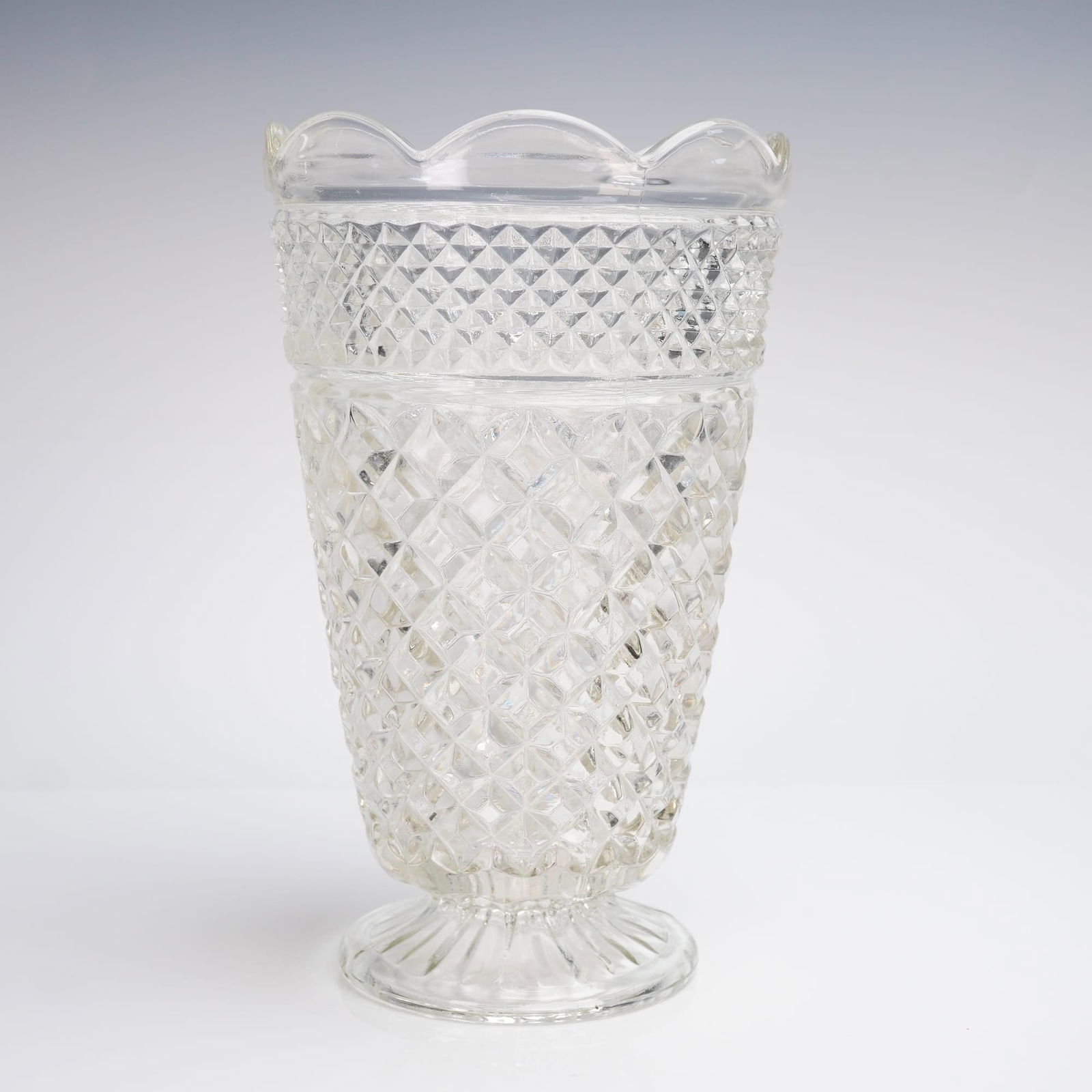 Anchor Hocking Wexford Pattern Clear Glass Footed Vase: A clear pressed glass vase in the highly recognizable Wexford pattern manufactured by Anchor Hocking. This footed glass vase features a tapered cylindrical body resting on a short, spreading pedestal