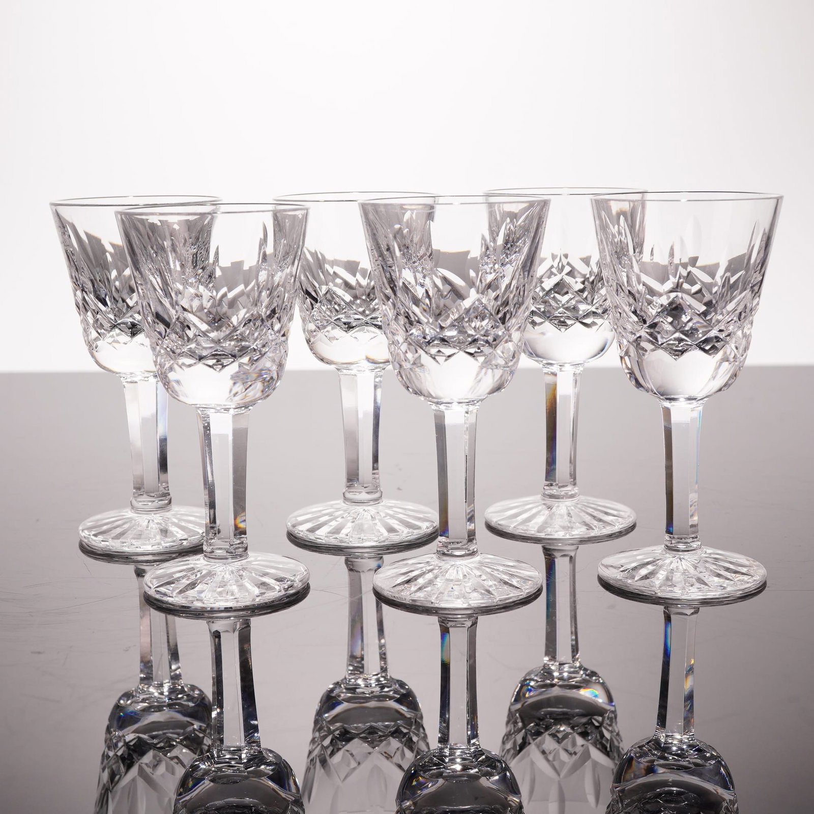 6pc Waterford Lismore Crystal Liqueur Glasses: This set of six fine lead crystal liqueur glasses is produced by Waterford Crystal in the iconic Lismore pattern. The design features the pattern's signature deep criss-cross diamond cuts on the lower