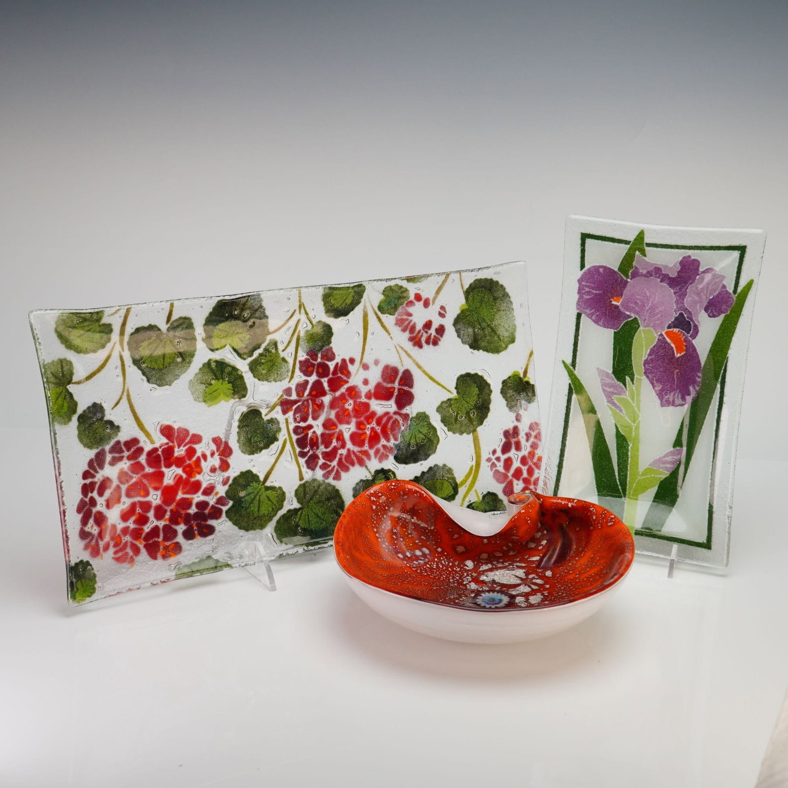 Three Fused Italian Art Glass Bowls and Trays: This lot features three pieces of contemporary decorative art glass, including two fused glass botanical trays and one hand-blown bowl. The first is a large rectangular platter created using fused and