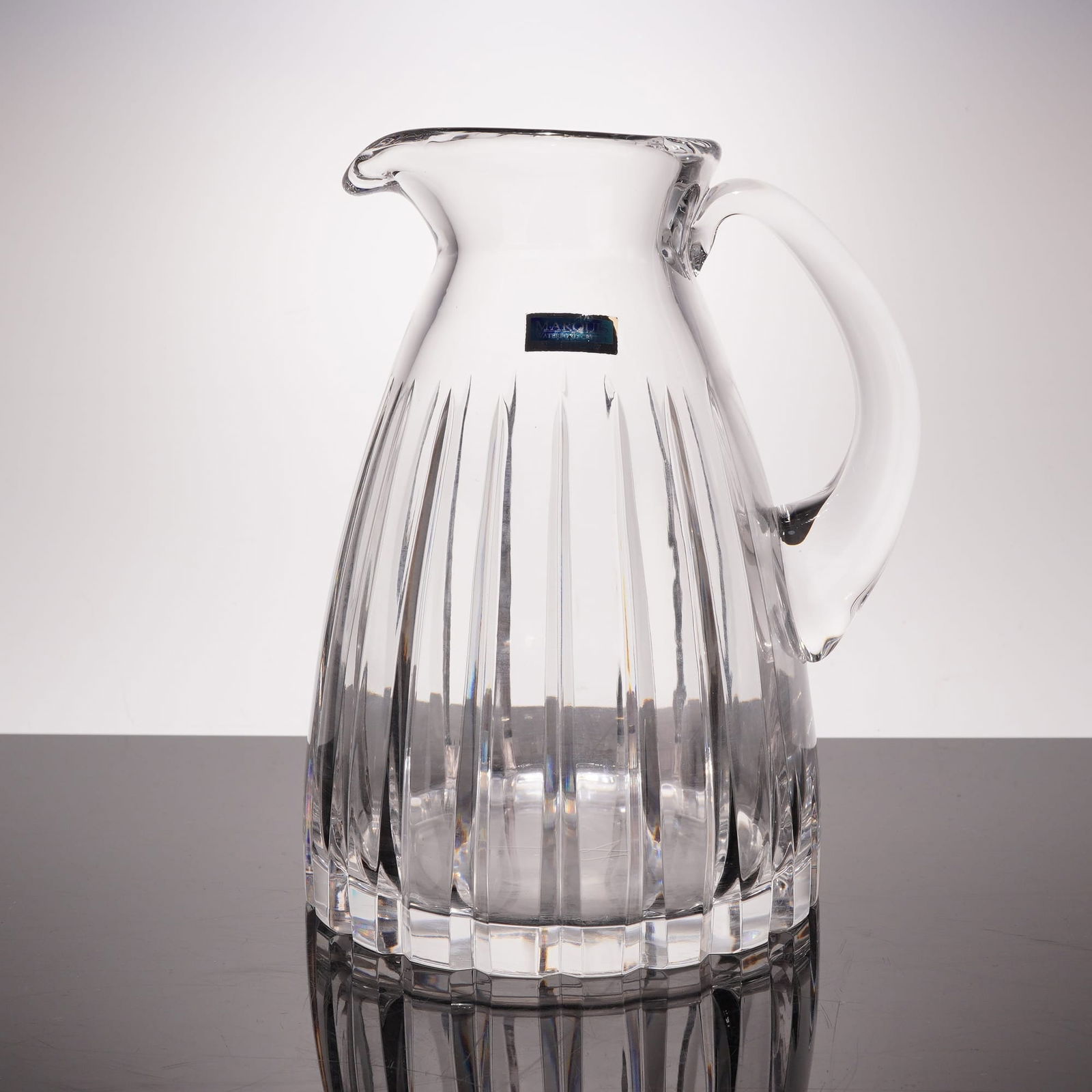 Marquis by Waterford Crystal Omega Pattern Water Pitcher: A fine lead crystal water pitcher from the Marquis by Waterford collection, executed in the Omega pattern. This elegant vessel features a tapered form decorated with bold, vertical pillar flutes or mi