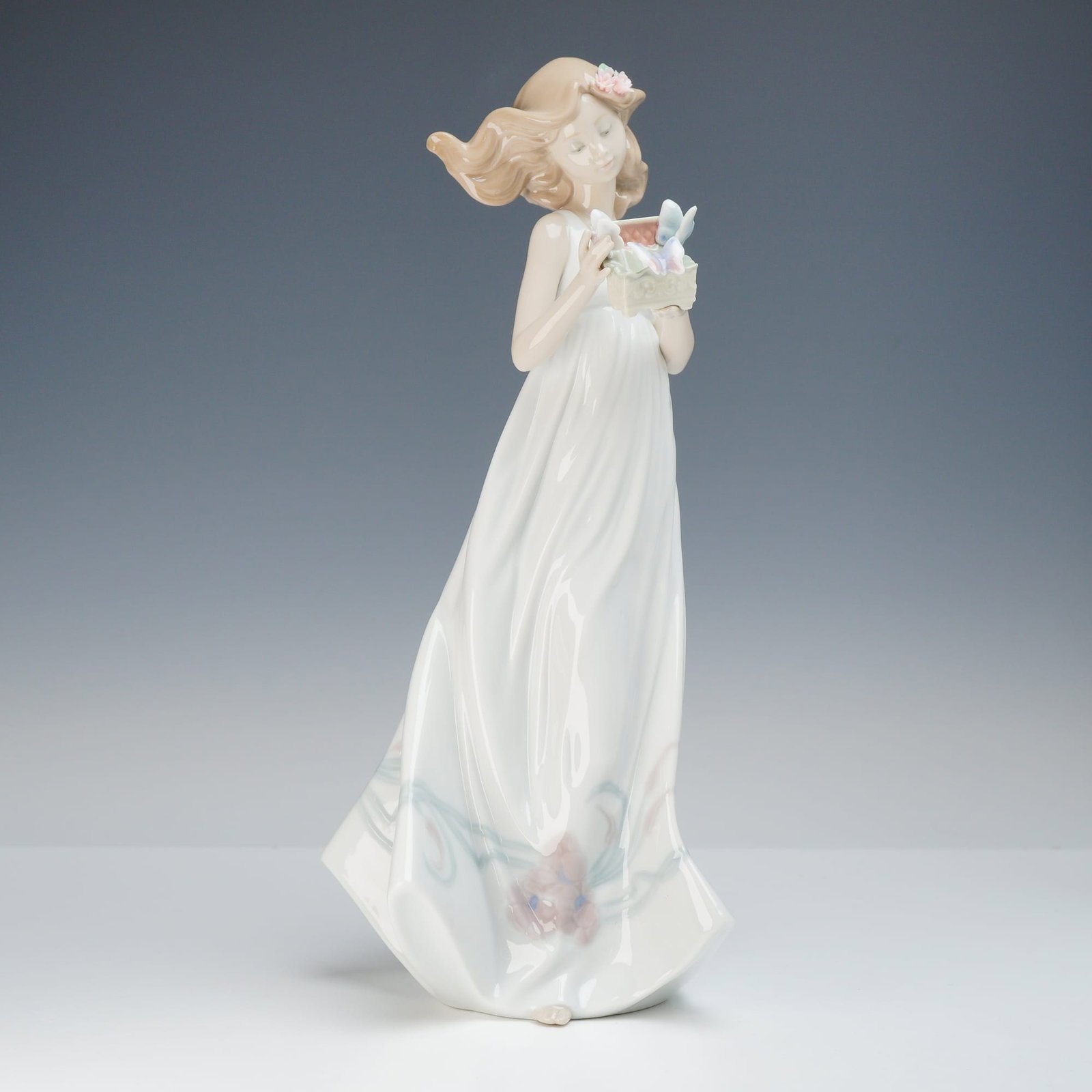 Lladró Butterfly Treasures Porcelain Figurine Model 6777: This glazed porcelain figurine is identified as Butterfly Treasures, model number 6777, manufactured by Lladró. The figure depicts a young woman in a long, windswept white dress holding a small recta