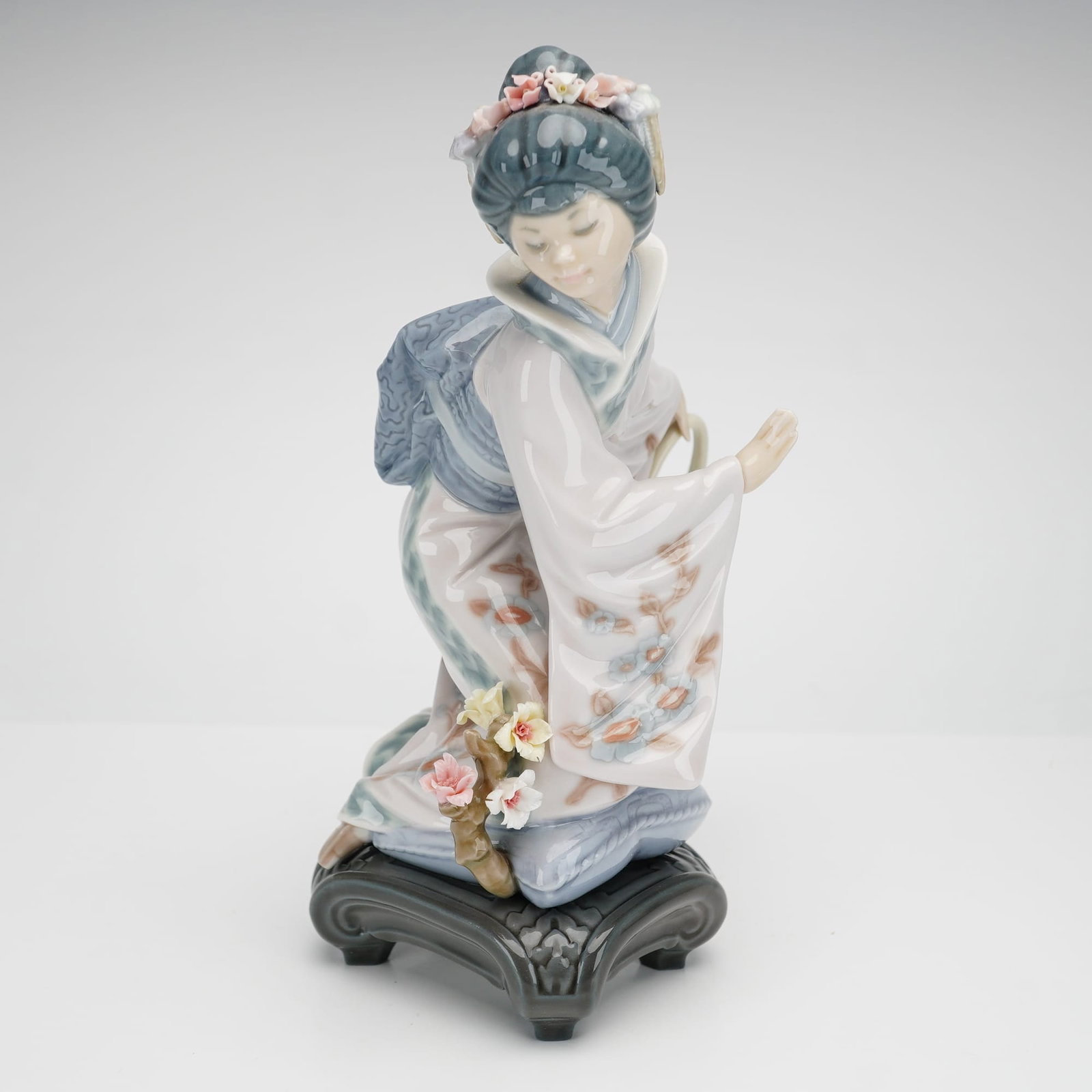 Lladró Porcelain Figurine, Michiko #01001447: A Lladró porcelain figurine titled Michiko, model number 01001447, designed by artist Salvador Debón. This glazed porcelain sculpture depicts a Japanese woman in a graceful kneeling position atop a