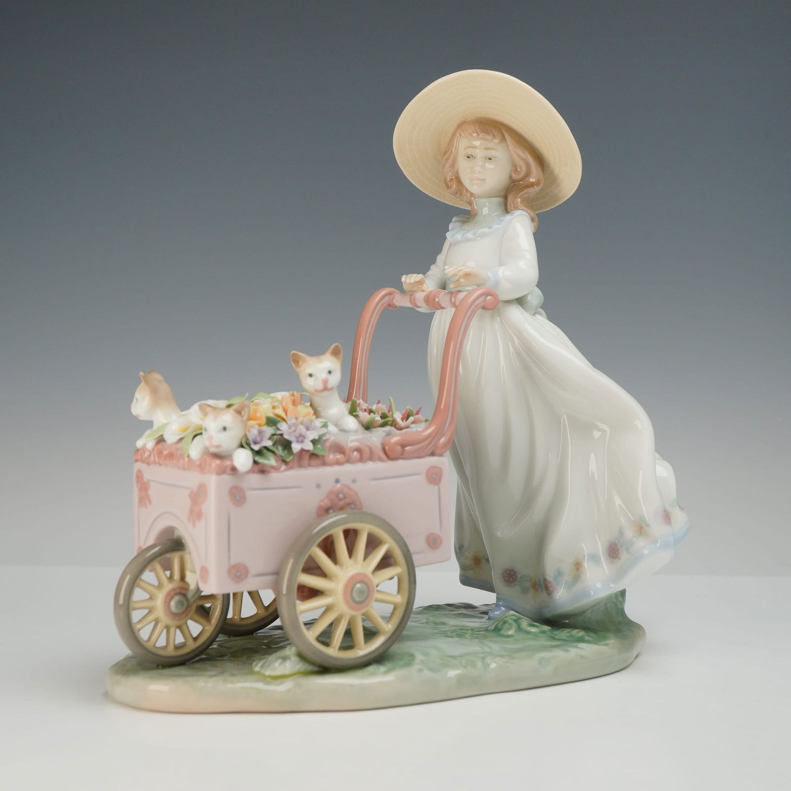 Lladro Kitty Cart Porcelain Figurine Number 6141: This glazed porcelain figurine, identified as Kitty Cart (model number 6141), was produced by the Lladro factory in Valencia, Spain. The sculpture depicts a young girl wearing a wide-brimmed sun hat a