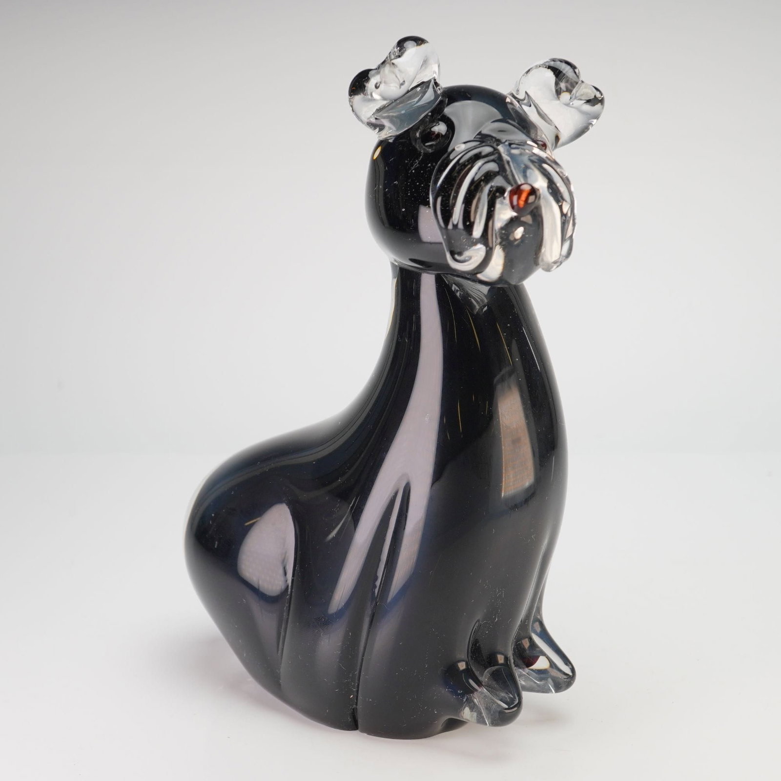Saks Fifth Avenue Solid Glass Terrier Dog Figurine: This professional hand-blown art glass figurine depicts a seated terrier, rendered in a stylized mid-century modern form. The body is composed of heavy, solid smoky black glass that appears opaque in