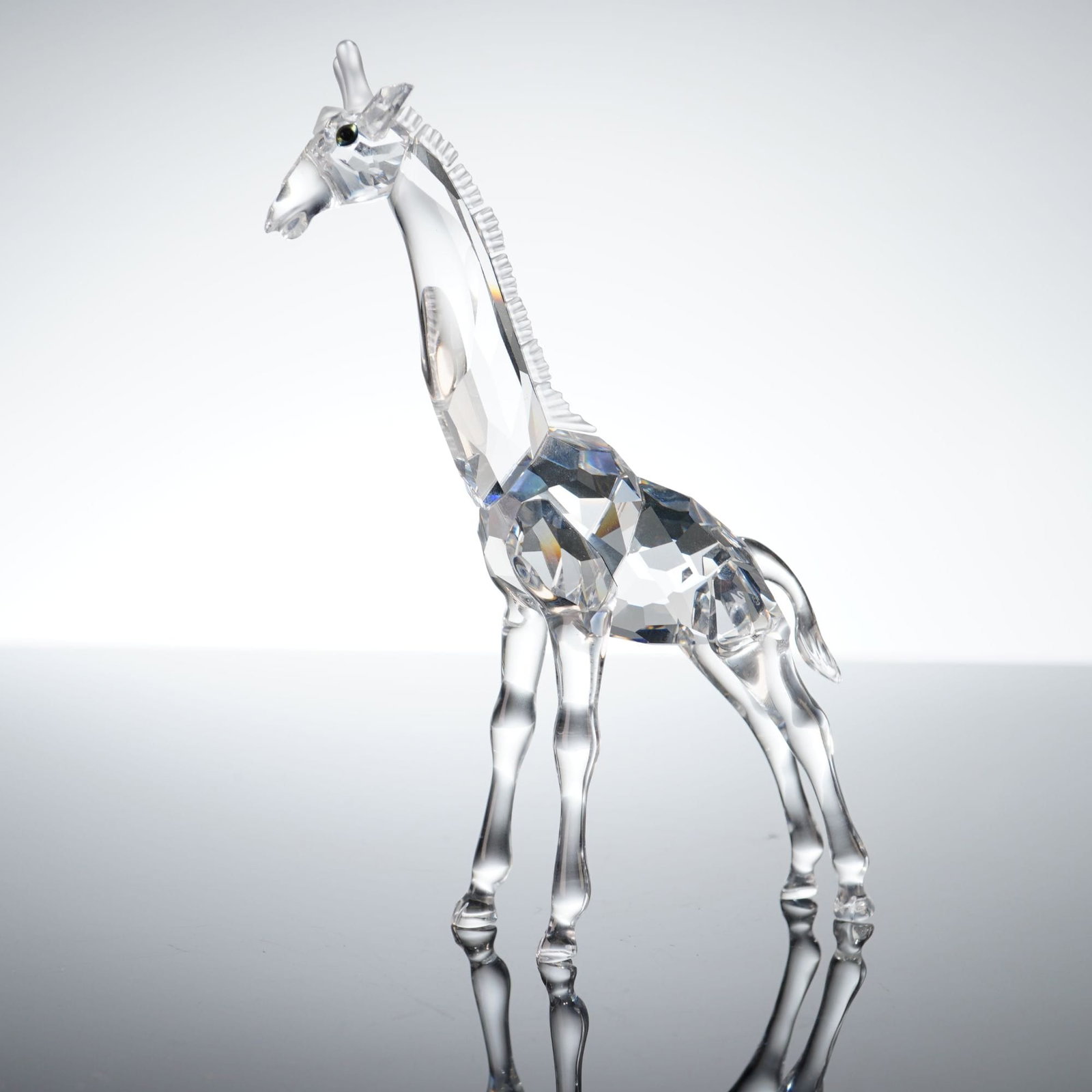 Swarovski Crystal African Wildlife Giraffe Figurine: This Swarovski crystal figurine depicts a standing giraffe from the African Wildlife collection. The sculpture is crafted from faceted lead crystal, with a body designed to refract light through multi