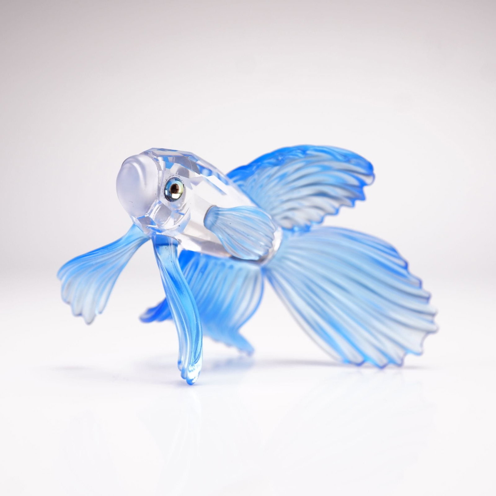 Swarovski Crystal Figurine Blue Siamese Fighting Fish 236718: The figurine is crafted with a central body of clear, high-lead-content crystal featuring large, precision-cut geometric facets that provide exceptional brilliance and light refraction. The elaborate