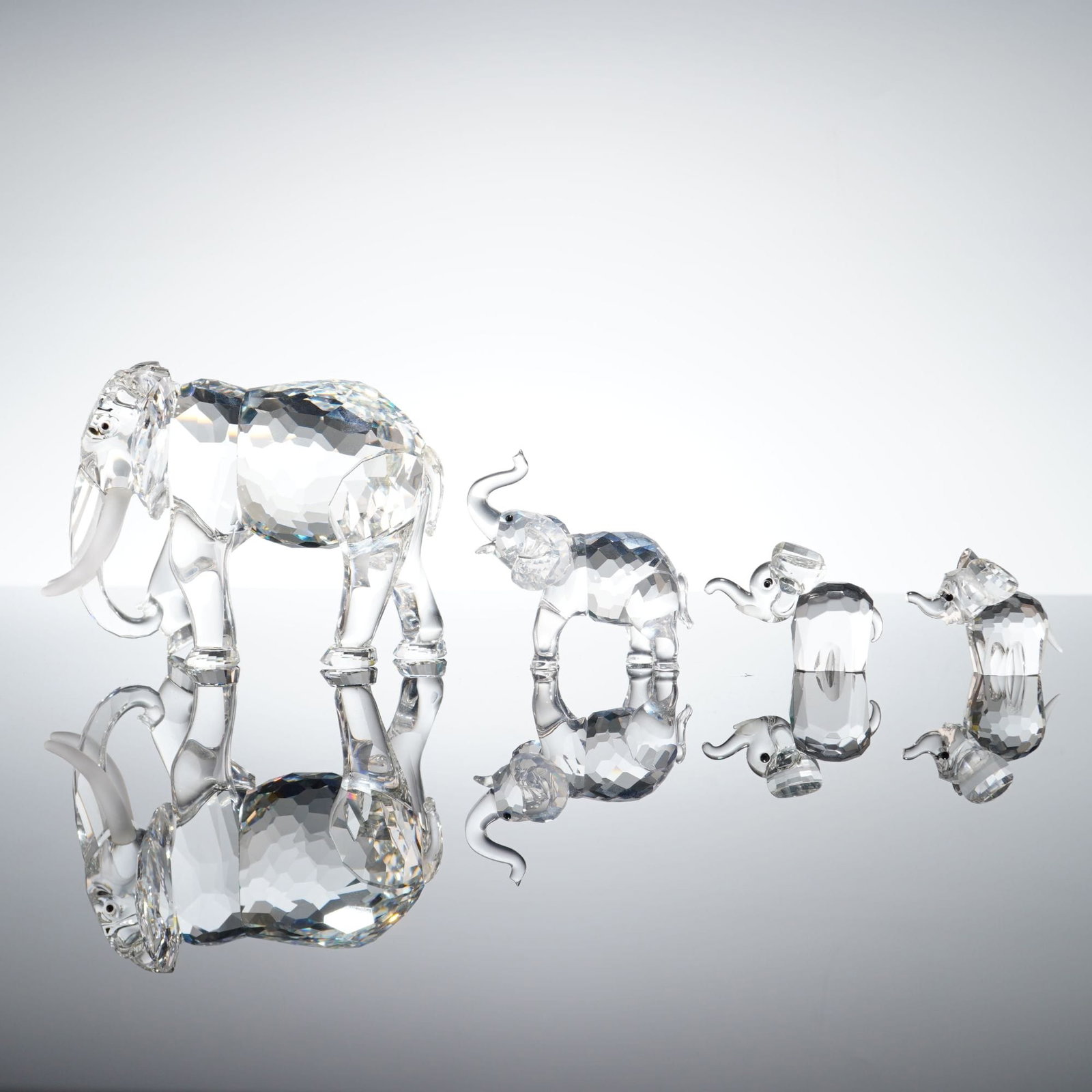 4pc Swarovski Faceted Lead Crystal Elephant Figurines: This collection of 4 elephants is manufactured by Swarovski and crafted from clear faceted lead crystal. The set consists of a family group in graduated sizes. The largest adult elephant features larg