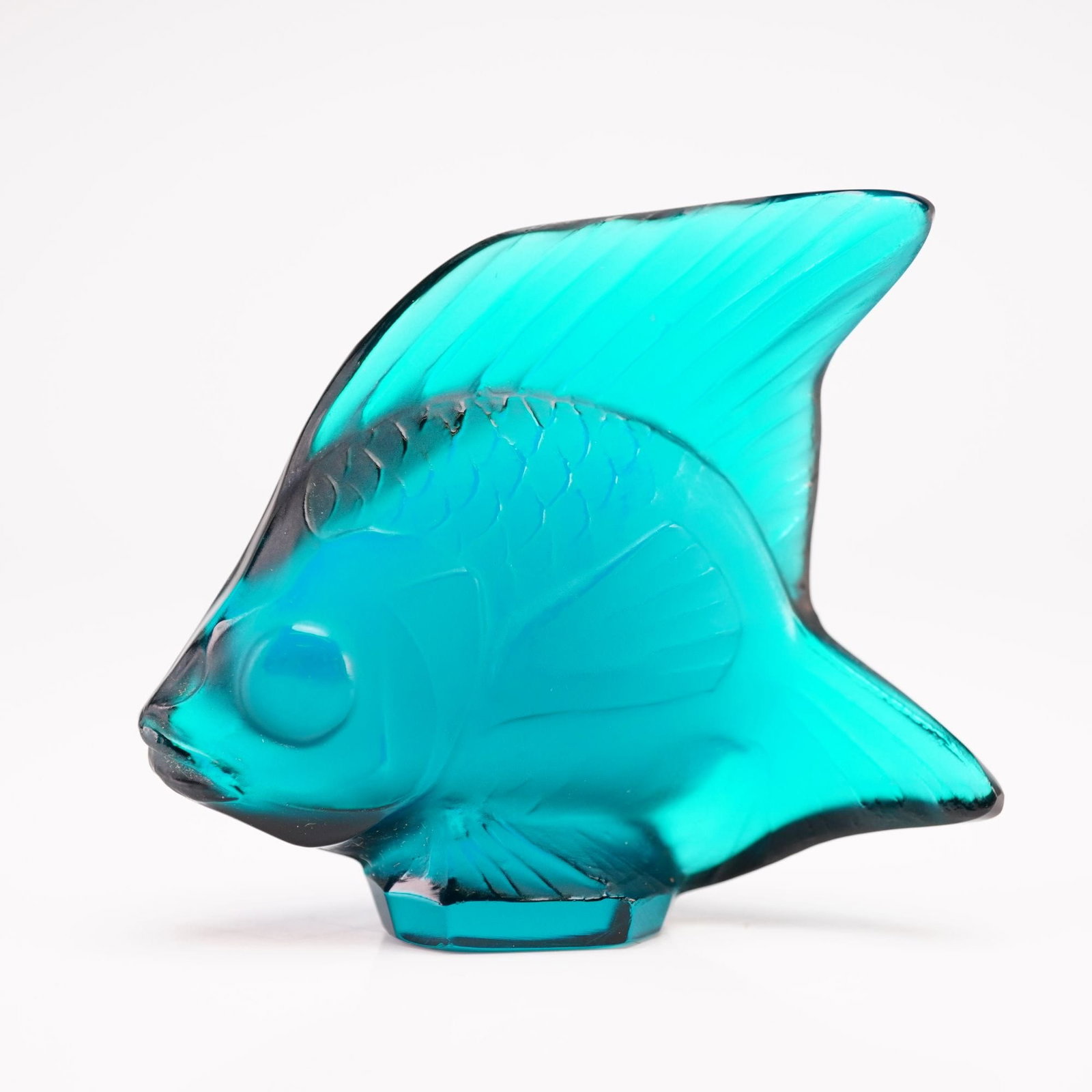 Lalique Crystal Pale Turquoise Fish Figurine: Executed in a vibrant translucent turquoise crystal this figure features a stylized, rounded body with detailed relief-molded scales and fins, accented by characteristic satin-finished details. The si