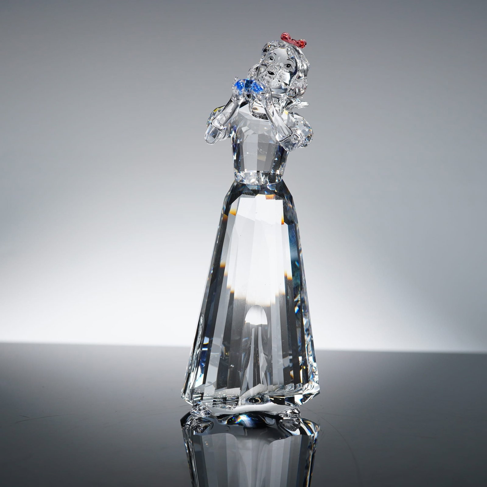 Swarovski Disney Snow White 994881, 5": Swarovski full-cut faceted lead crystal figurine, model 994881. This miniature depicts the Disney character Snow White holding a small blue crystal bird. The piece features a clear crystal body with a