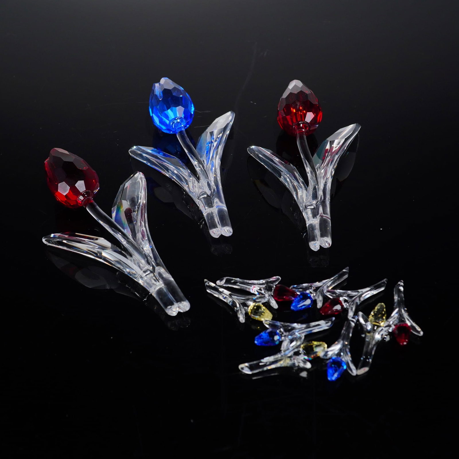 Swarovski Precision-Faceted Lead Crystal Tulip Figurines: A collection of Swarovski lead crystal figurines featuring the 3pc Swarovski Crystal Figurine set, model 626481, and a group of miniature tulips, model 606546. The collection includes three large tuli